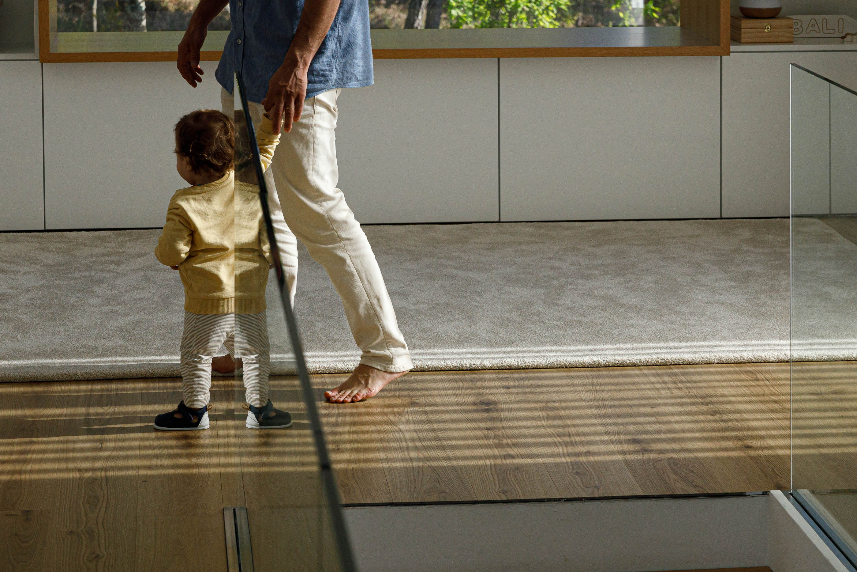 Sala de estar: Pavimento em madeira, alcatifa e pessoa a caminhar com criança. — Casa em Mundão arquitetura Um para Um, arquitectura e engenharia em Viseu