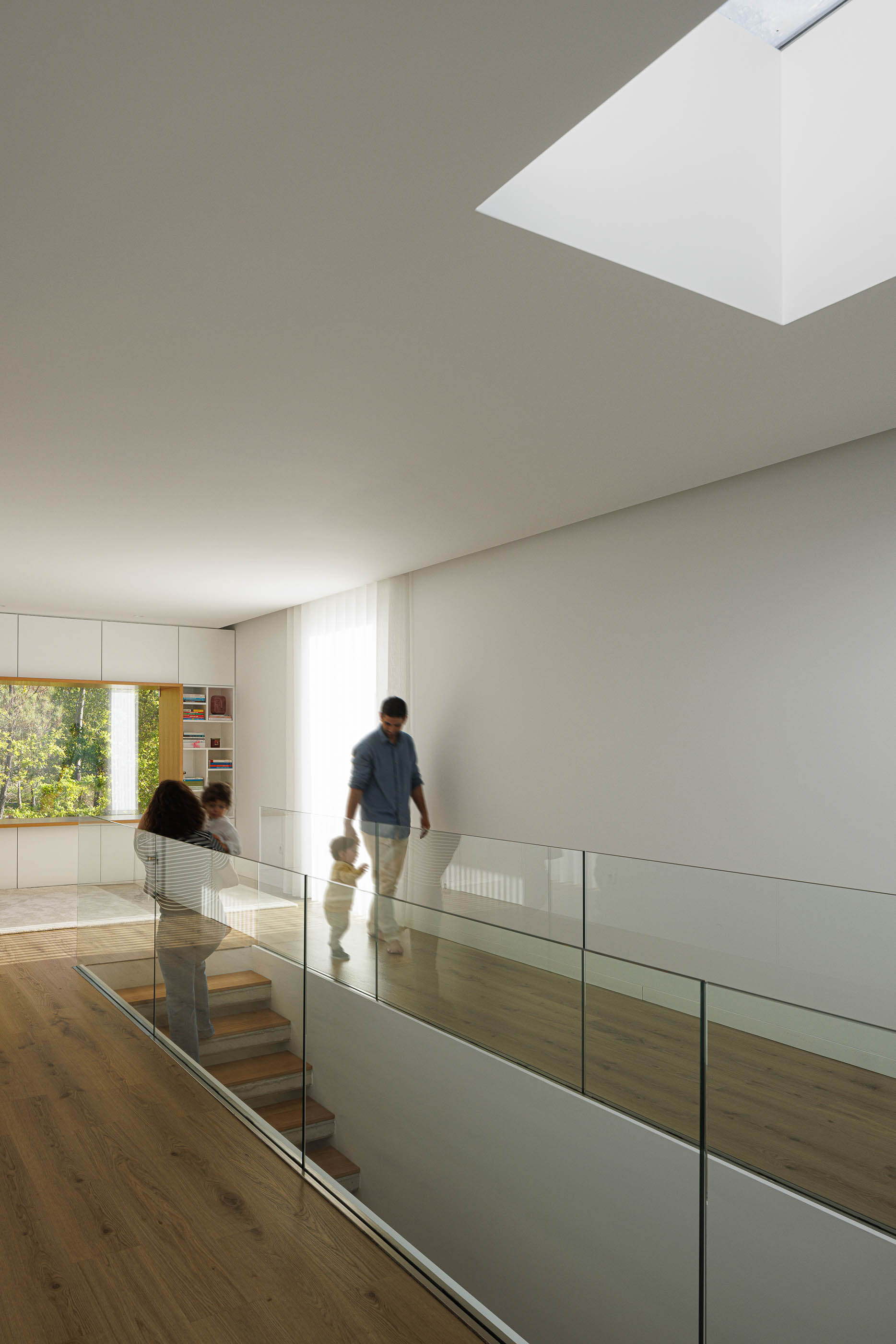 Hall: Escadas em madeira com iluminação, guarda em vidro e claraboia no teto. — Casa em Mundão arquitetura Um para Um, arquitectura e engenharia em Viseu