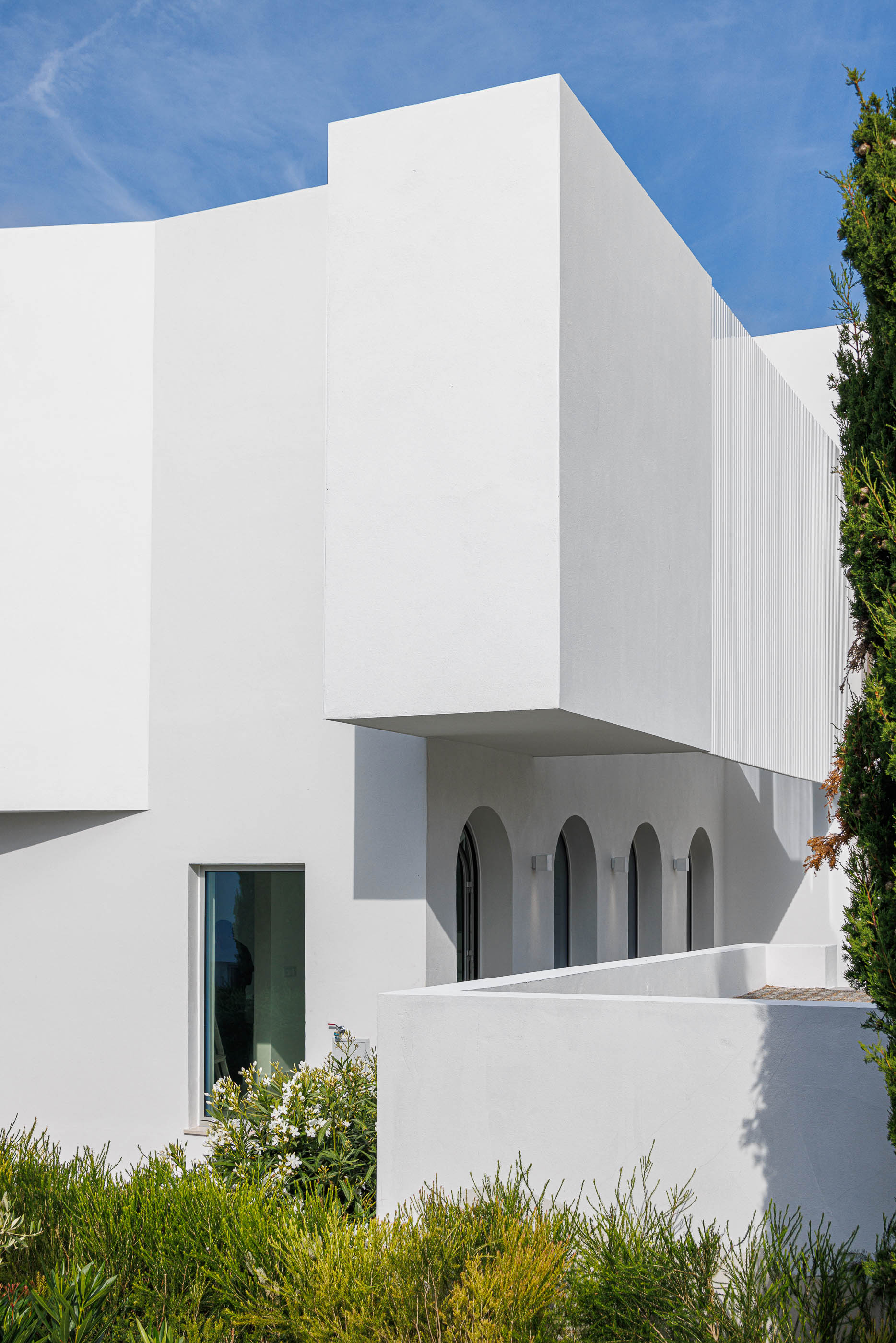 Exterior: Fachada branca com volumes geométricos e vegetação. — Villa Fortaleza arquitetura Vieira de Moura Architects em Algarve