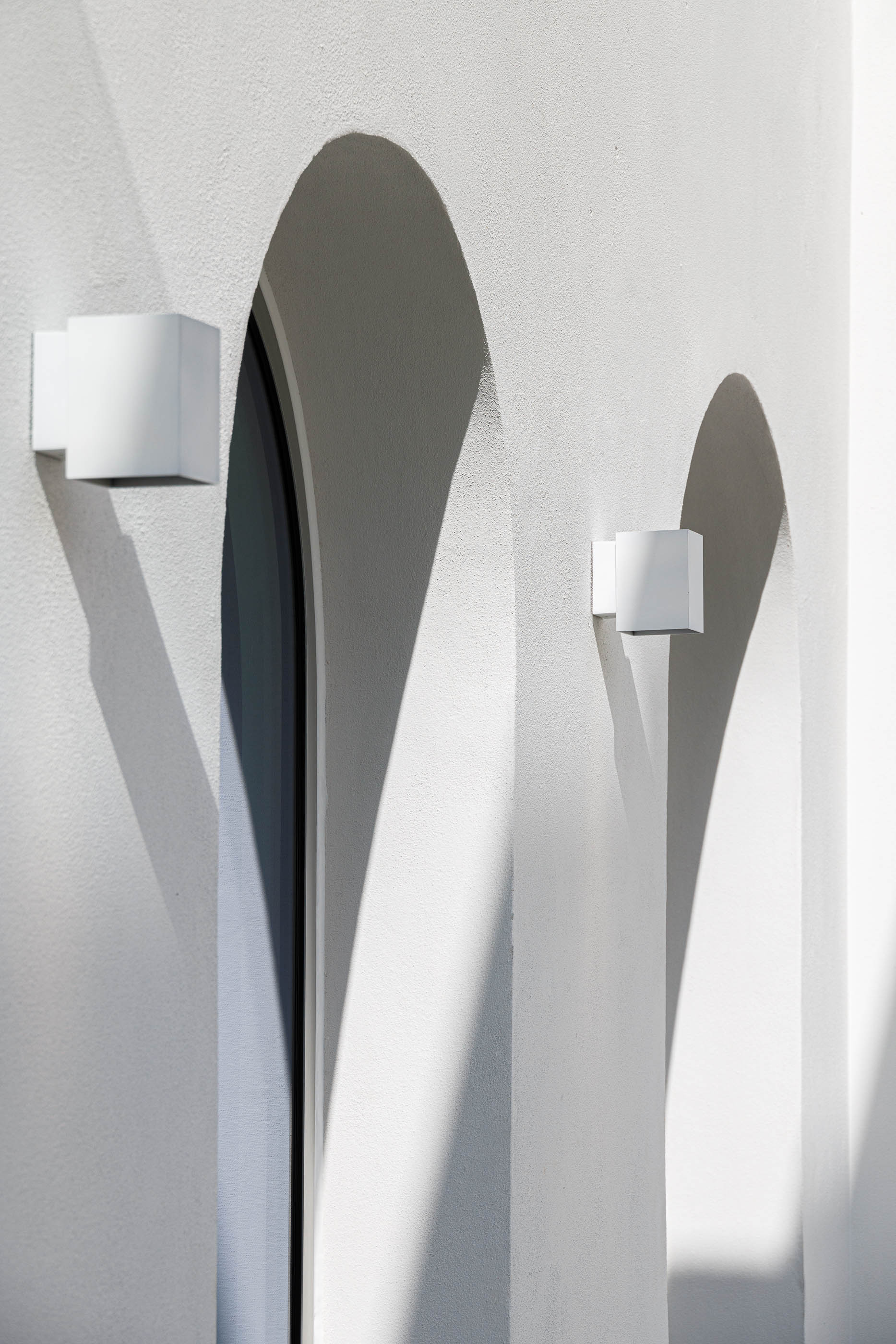 Exterior: Detalhe de arcos brancos com candeeiros de parede cúbicos. — Villa Fortaleza arquitetura Vieira de Moura Architects em Algarve