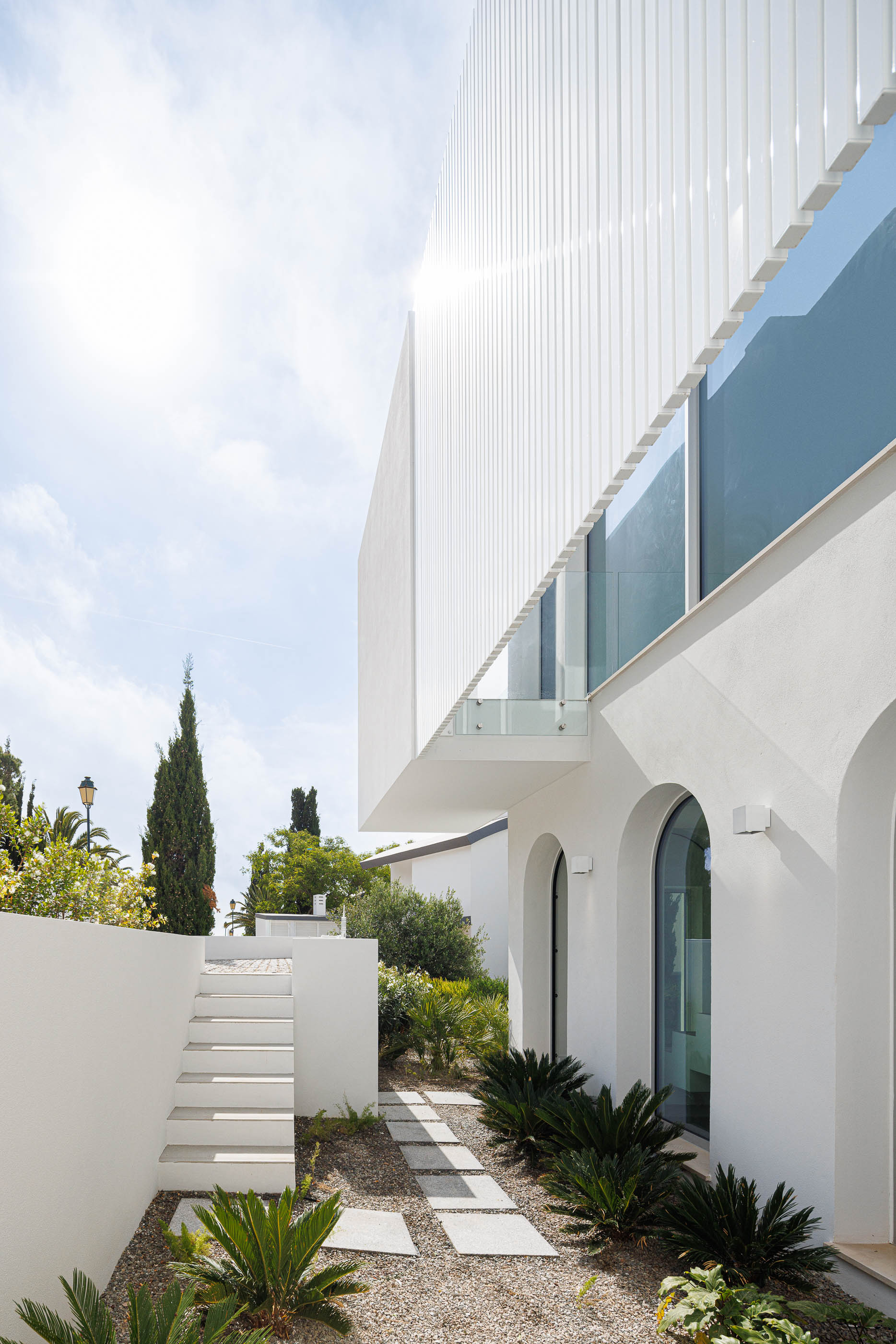Exterior: Escadaria branca que conduz à entrada, fachada com ripas verticais. — Villa Fortaleza arquitetura Vieira de Moura Architects em Algarve
