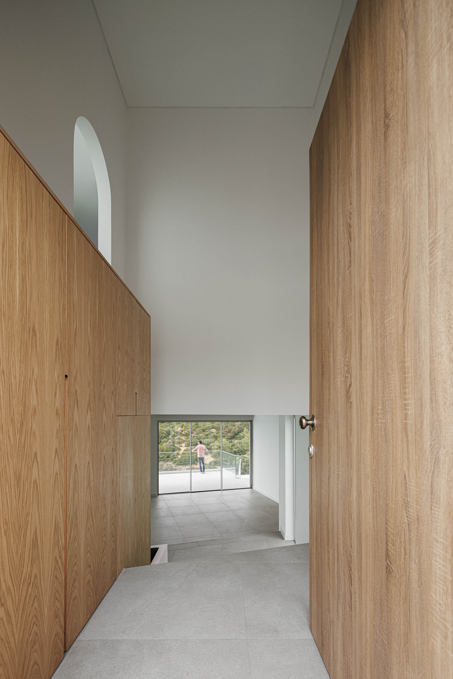Hall de entrada: Escadas em pedra, armário em madeira, vista para o exterior. — Villa Fortaleza arquitetura Vieira de Moura Architects em Algarve