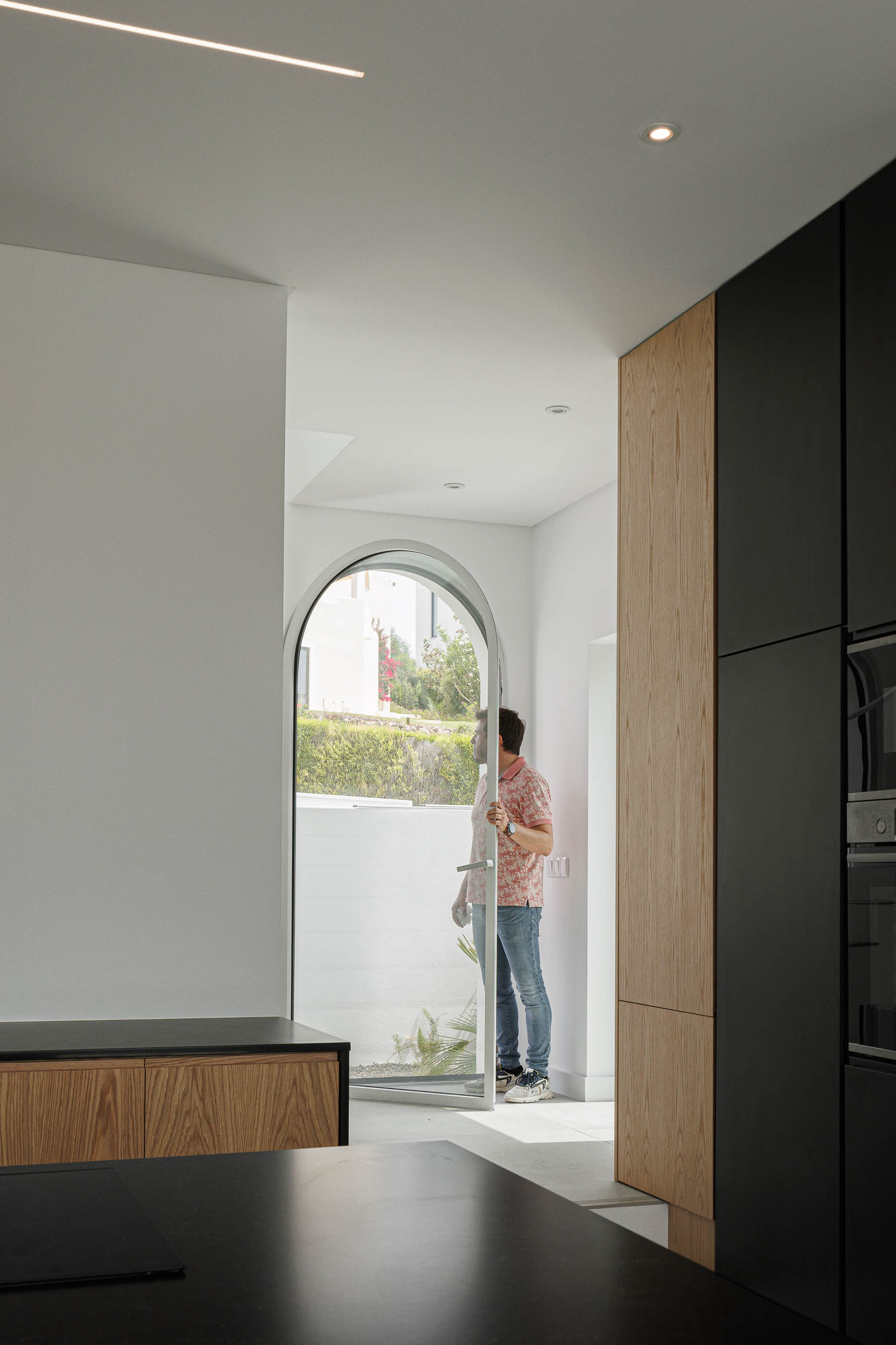 Cozinha: Detalhe de armários pretos e madeira, janela em arco. — Villa Fortaleza arquitetura Vieira de Moura Architects em Algarve