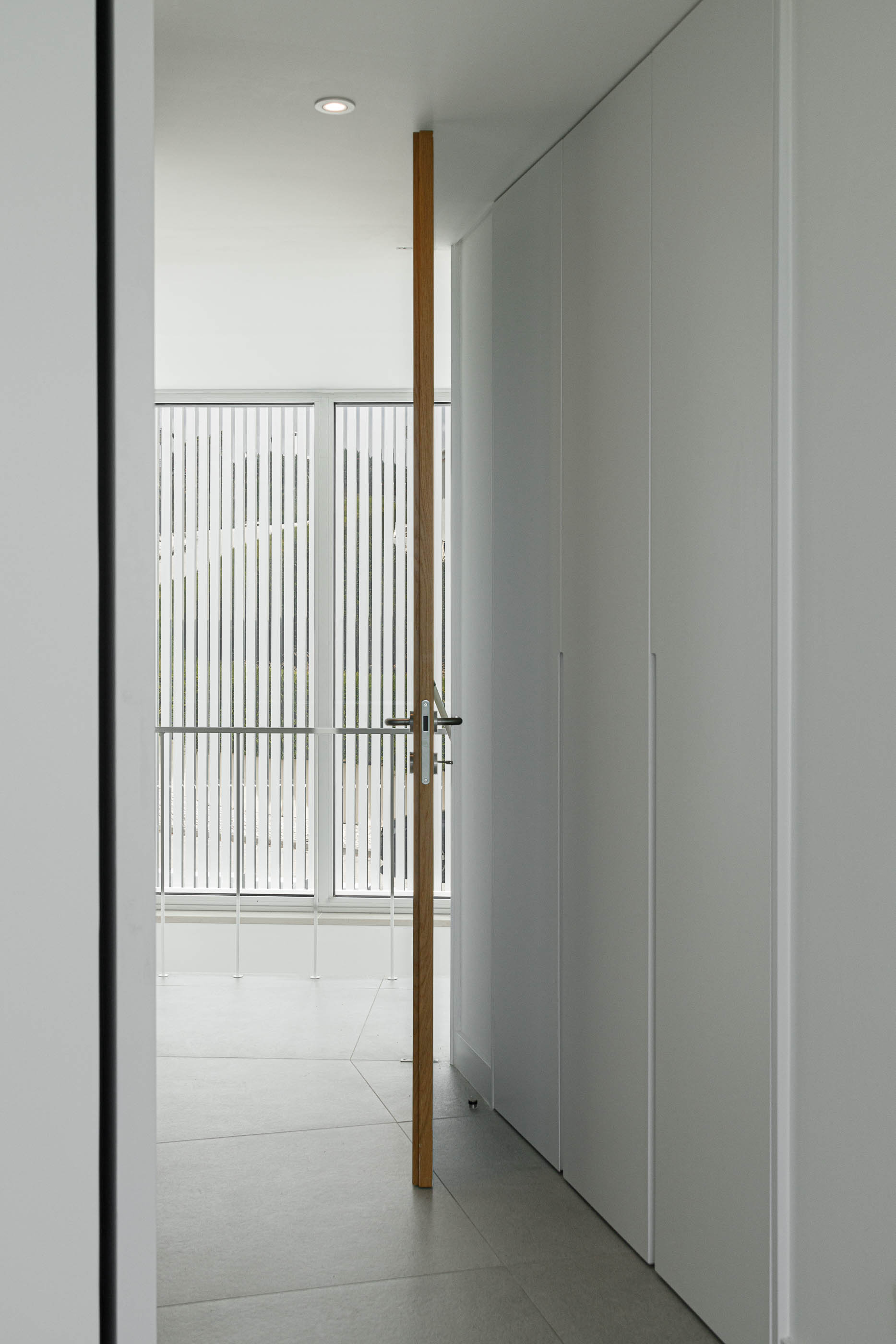 Corredor: Porta em madeira clara, armários brancos embutidos. — Villa Fortaleza arquitetura Vieira de Moura Architects em Algarve