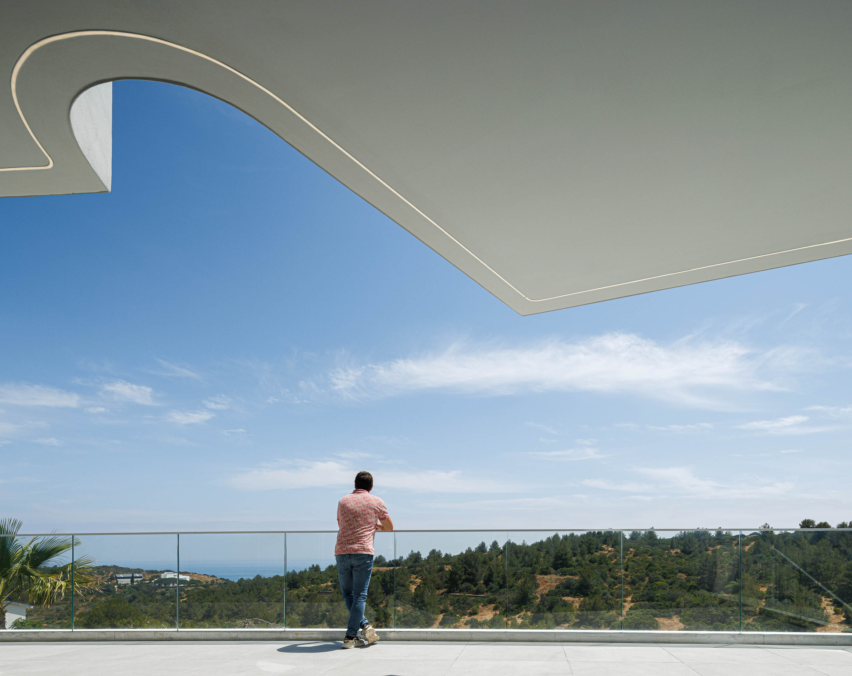 Varanda: Vista panorâmica para a paisagem, teto curvo com iluminação. — Villa Fortaleza arquitetura Vieira de Moura Architects em Algarve