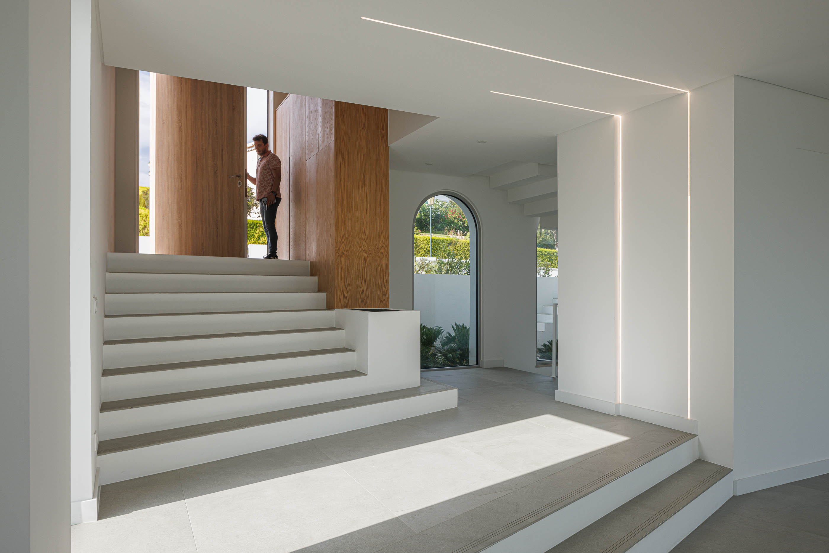 Hall de entrada: Escadas em pedra, porta de entrada em madeira aberta. — Villa Fortaleza arquitetura Vieira de Moura Architects em Algarve