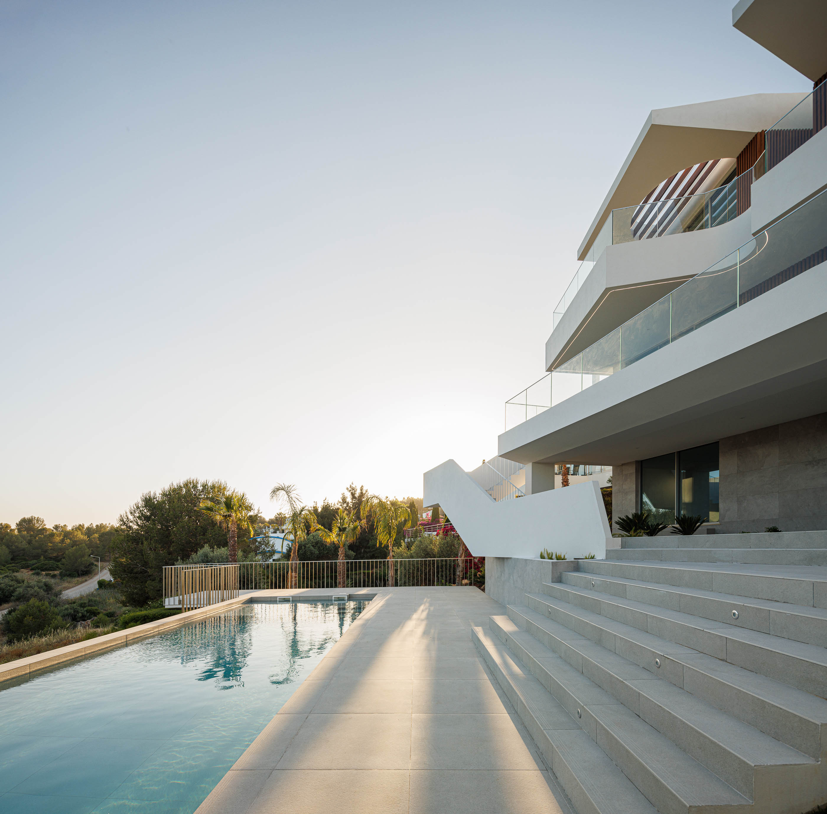 Exterior: Piscina com acesso por escadas, moradia ao fundo. — Villa Fortaleza arquitetura Vieira de Moura Architects em Algarve