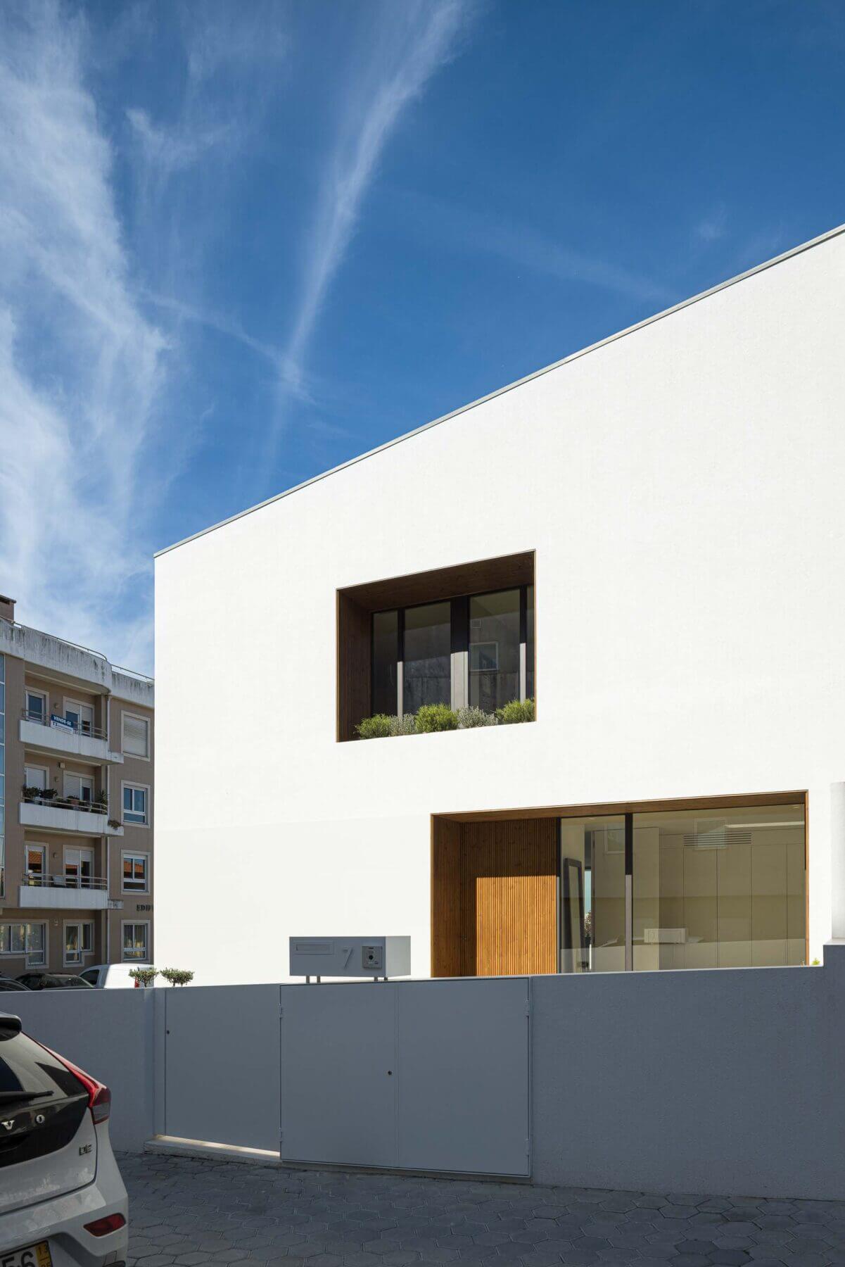 Fachada: Entrada da casa com porta de madeira e caixa de correio moderna, destacando a simplicidade do design. — Casa Forca-Vouga arquitetura RVDM - Ricardo Vieira de Melo, arquitectos em Aveiro