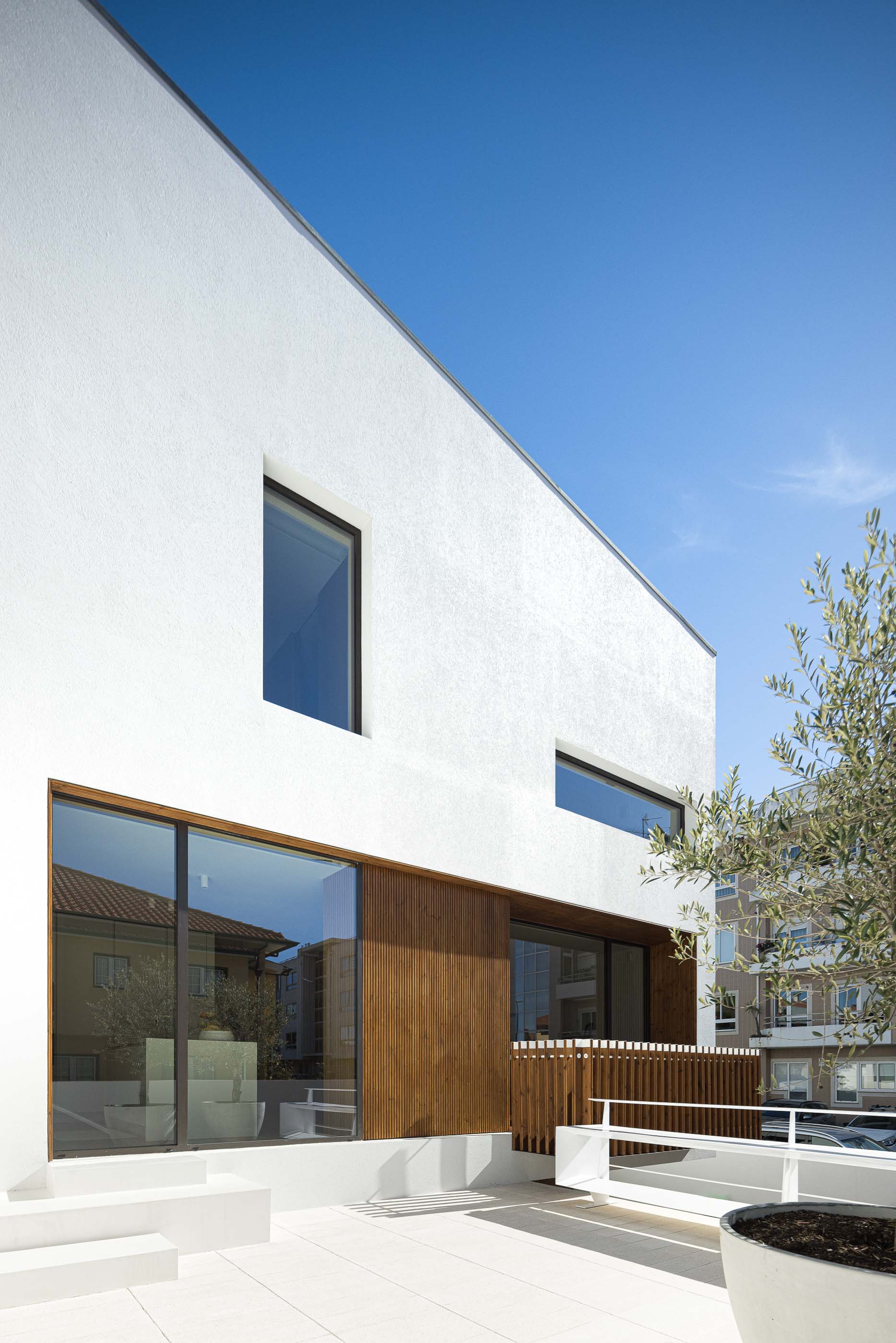 Terraço: Vista da fachada da casa a partir do terraço, com detalhes em madeira e plantas. — Casa Forca-Vouga arquitetura RVDM - Ricardo Vieira de Melo, arquitectos em Aveiro