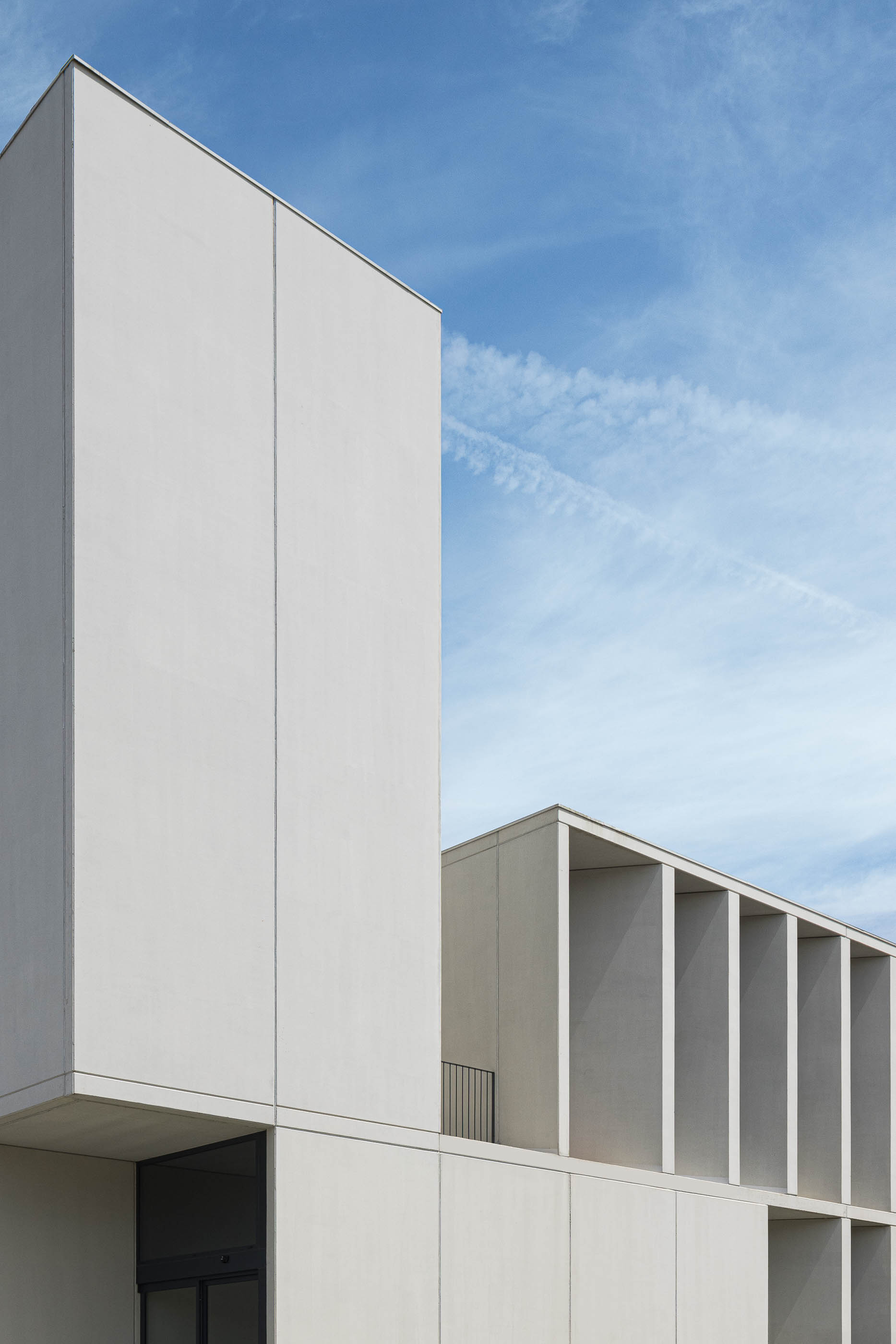 Exterior: Detalhe da fachada em betão branco, com janelas e varanda minimalista. — BW II – Edifício Industrial em Viana do Castelo arquitetura Multiprojectus em Viana do Castelo