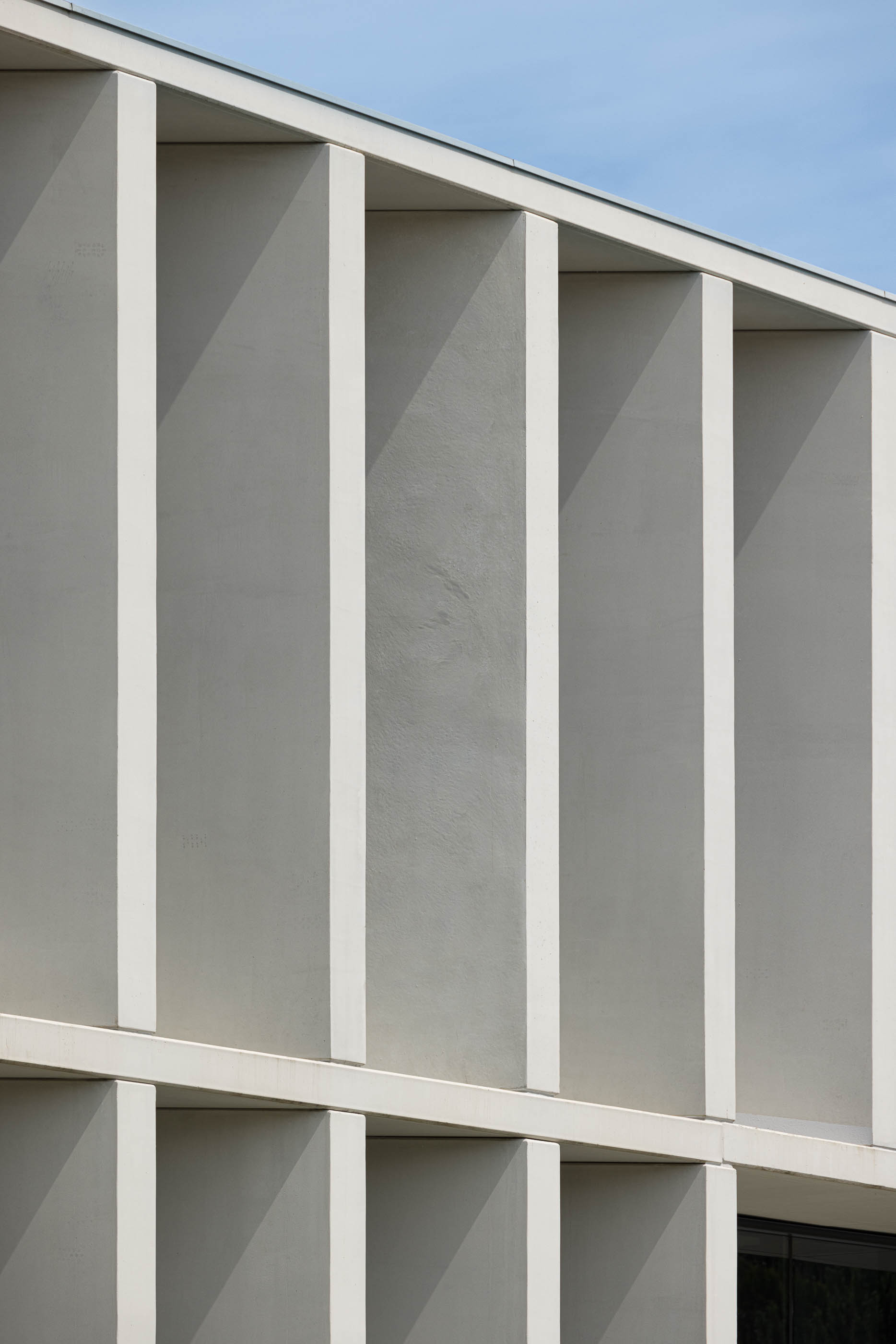 Fachada: Pormenor das colunas de betão branco, com janelas e estrutura geométrica. — BW II – Edifício Industrial em Viana do Castelo arquitetura Multiprojectus em Viana do Castelo