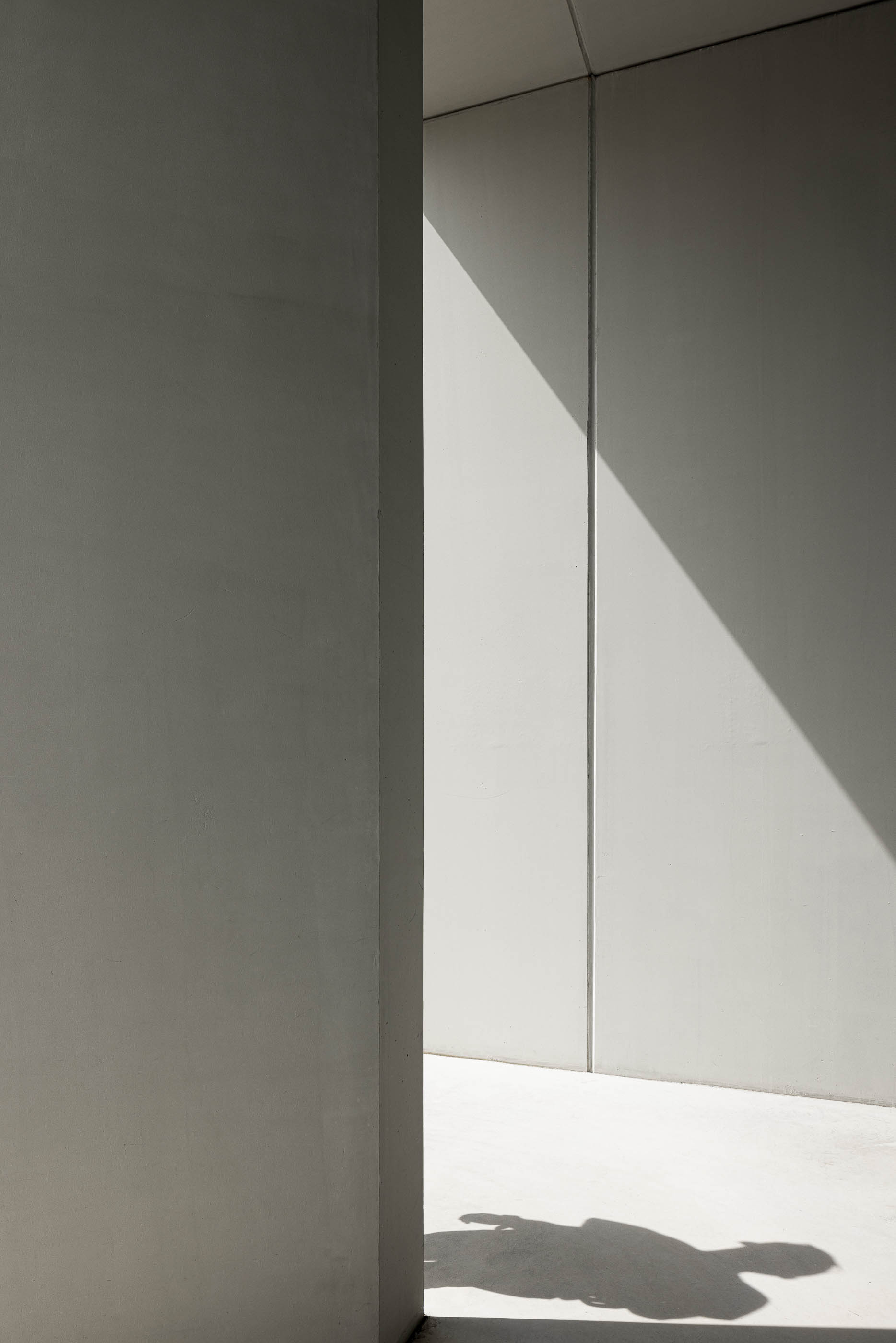 Exterior: Detalhe de parede em betão branco com sombra e pavimento claro. — BW II – Edifício Industrial em Viana do Castelo arquitetura Multiprojectus em Viana do Castelo
