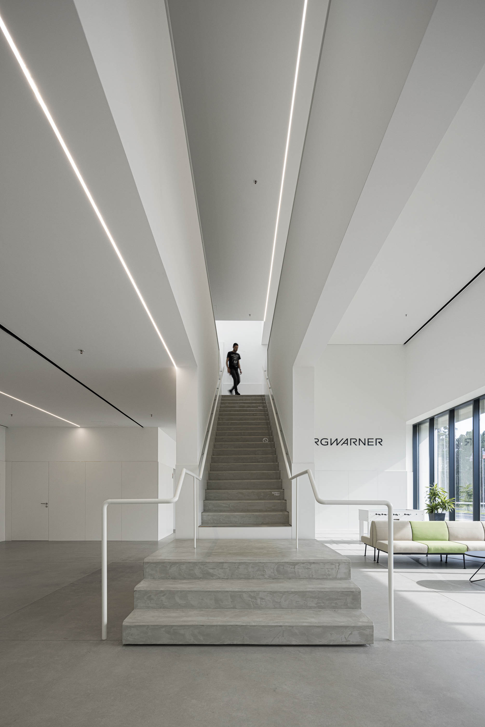 Escadaria: Escadas em betão com corrimão branco, integradas no hall de entrada amplo. — BW II – Edifício Industrial em Viana do Castelo arquitetura Multiprojectus em Viana do Castelo