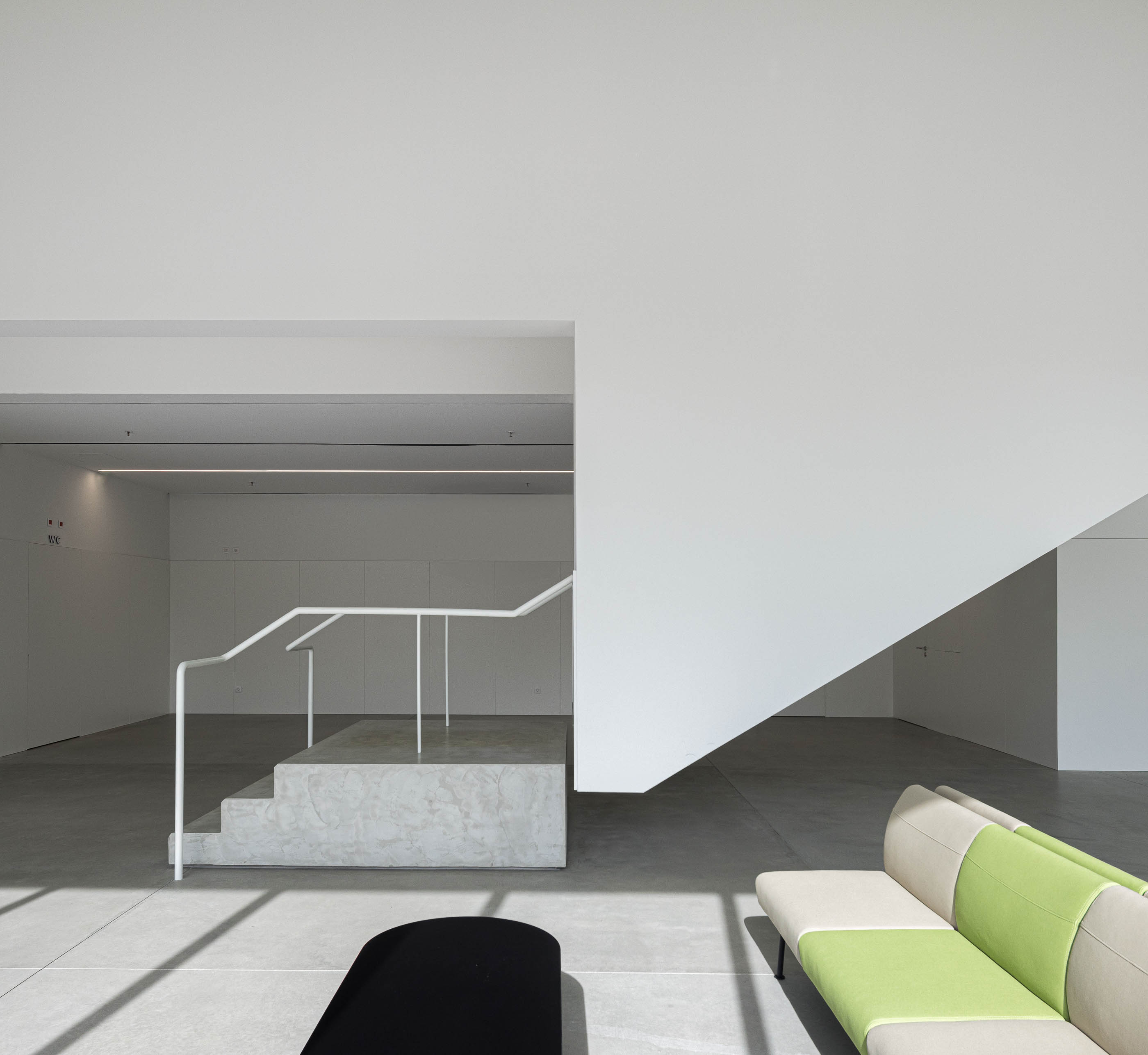Hall de entrada: Pormenor das escadas em betão, corrimão branco e pavimento em betão polido. — BW II – Edifício Industrial em Viana do Castelo arquitetura Multiprojectus em Viana do Castelo