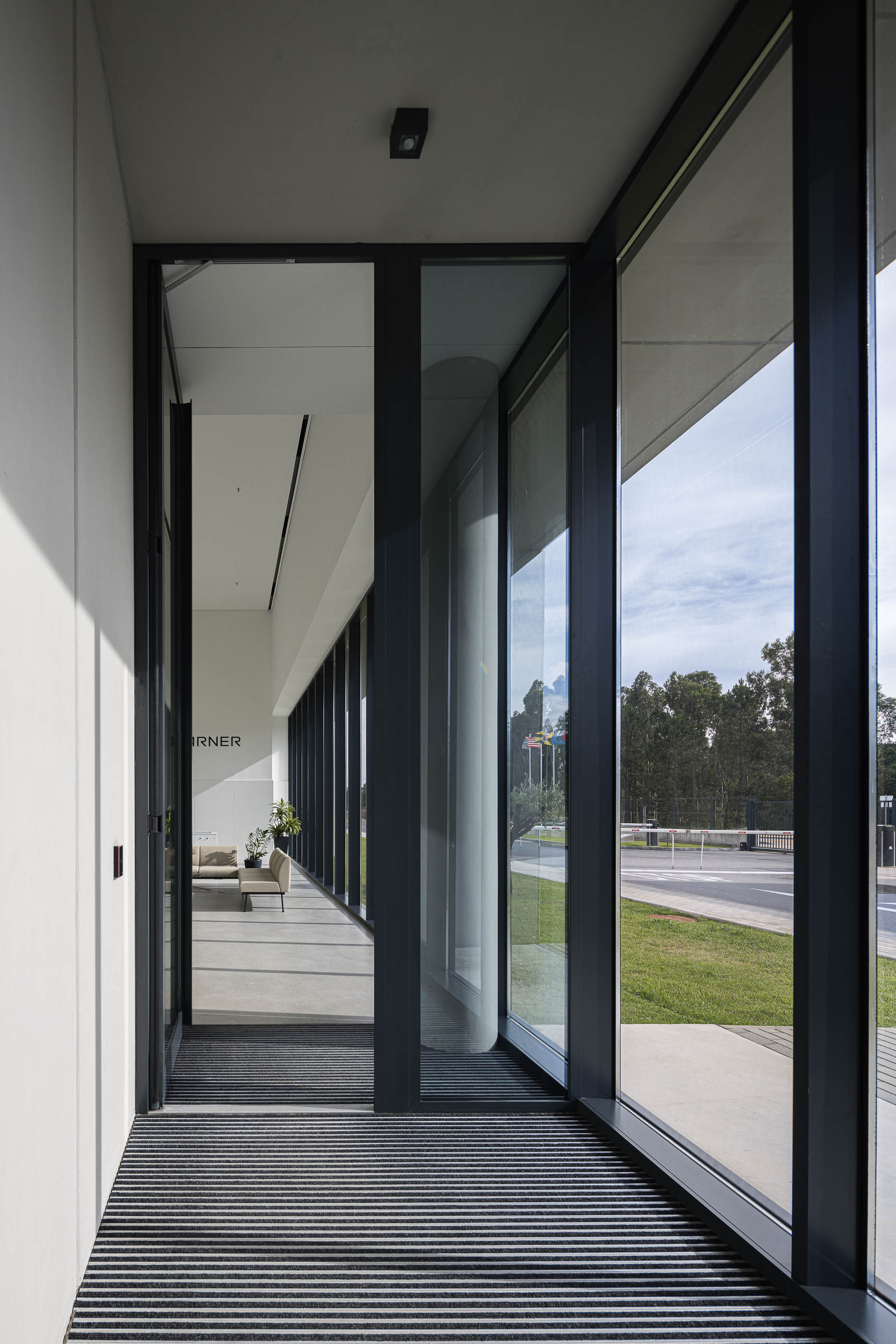 Corredor: Corredor industrial com paredes em betão, tubagens expostas e janelas para a produção. — BW II – Edifício Industrial em Viana do Castelo arquitetura Multiprojectus em Viana do Castelo