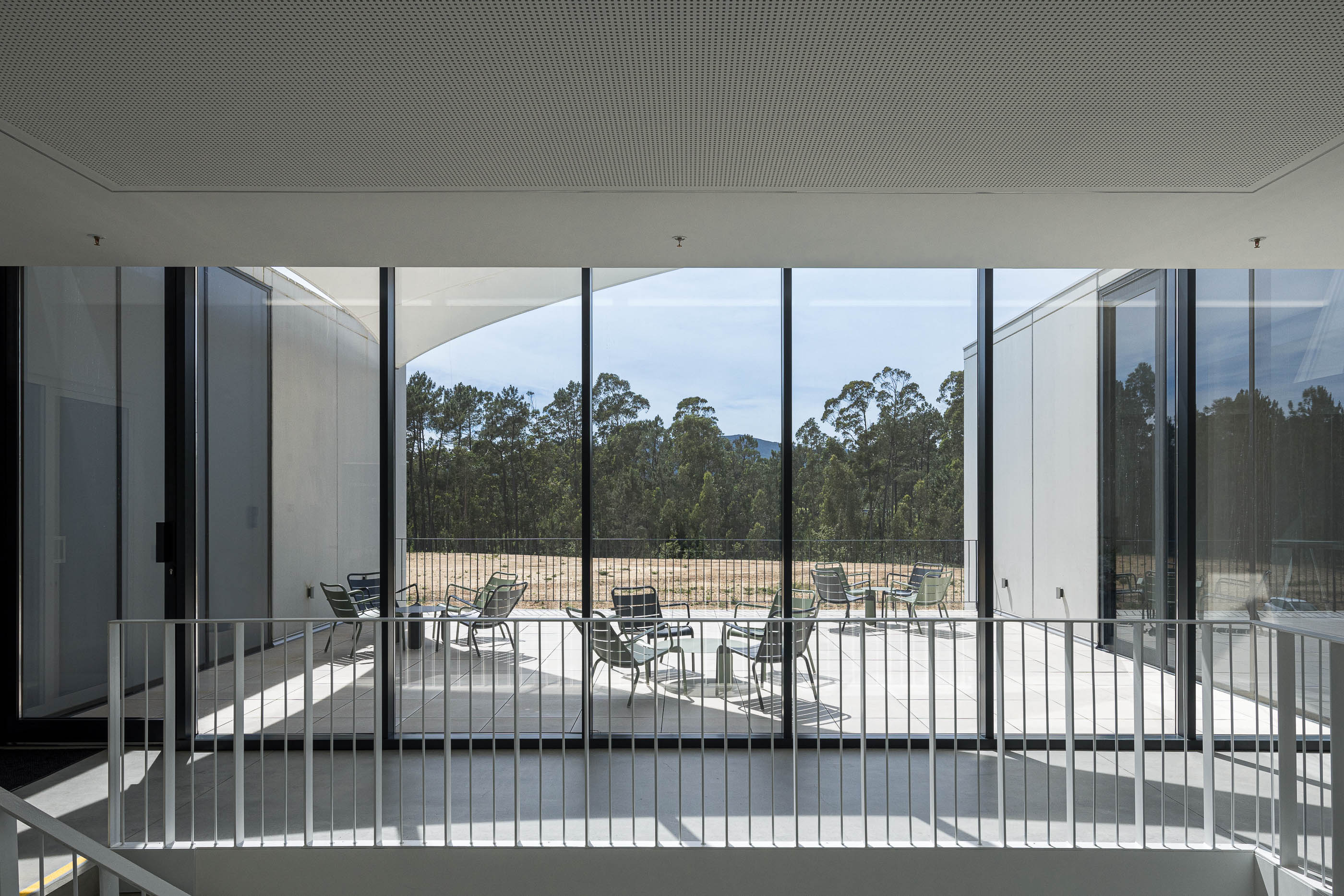 Escritório: Espaço de trabalho com secretárias, cadeiras pretas e janelas amplas. — BW II – Edifício Industrial em Viana do Castelo arquitetura Multiprojectus em Viana do Castelo
