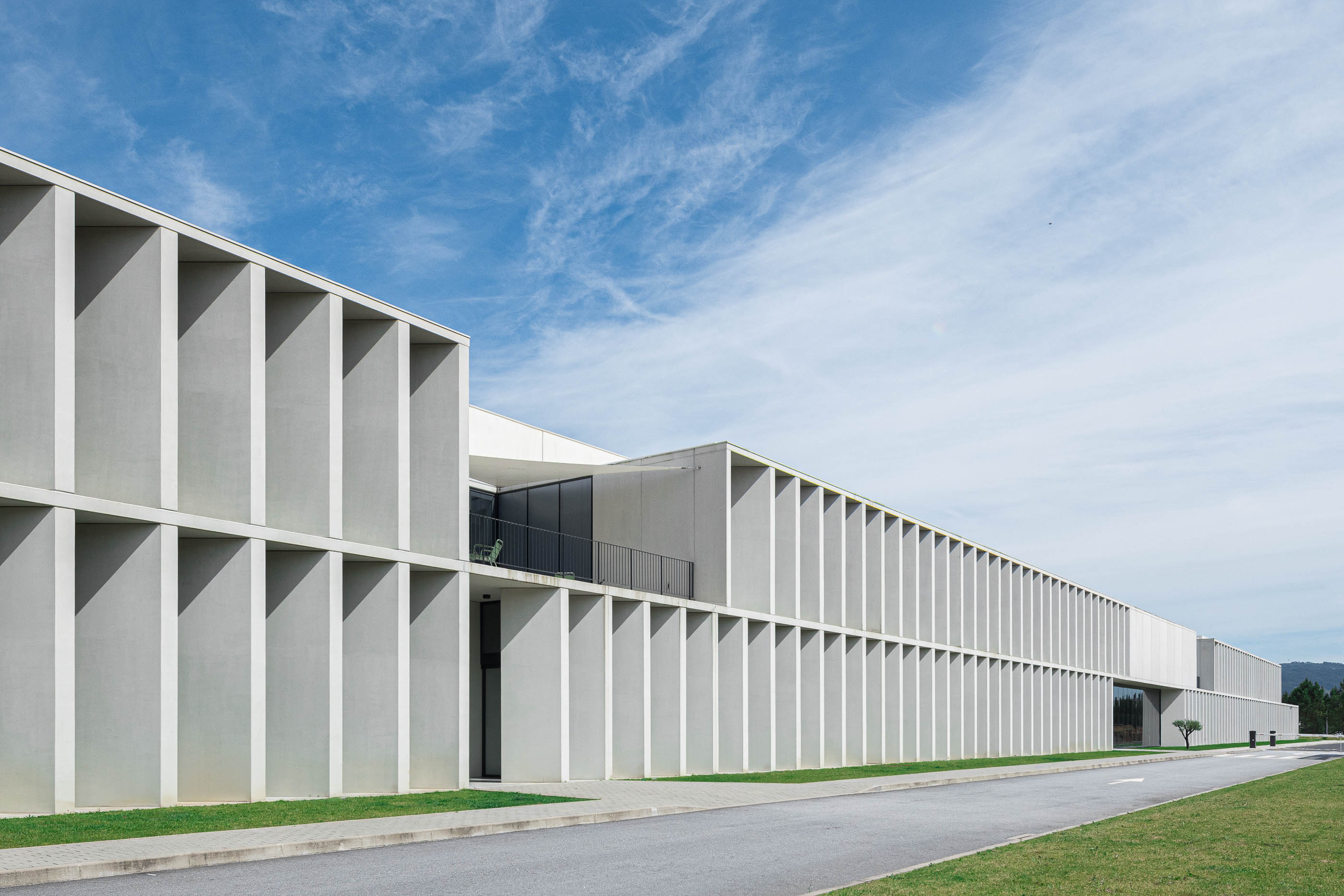 Exterior: Vista enquadrada do edifício industrial através de uma estrutura em betão. — BW II – Edifício Industrial em Viana do Castelo arquitetura Multiprojectus em Viana do Castelo