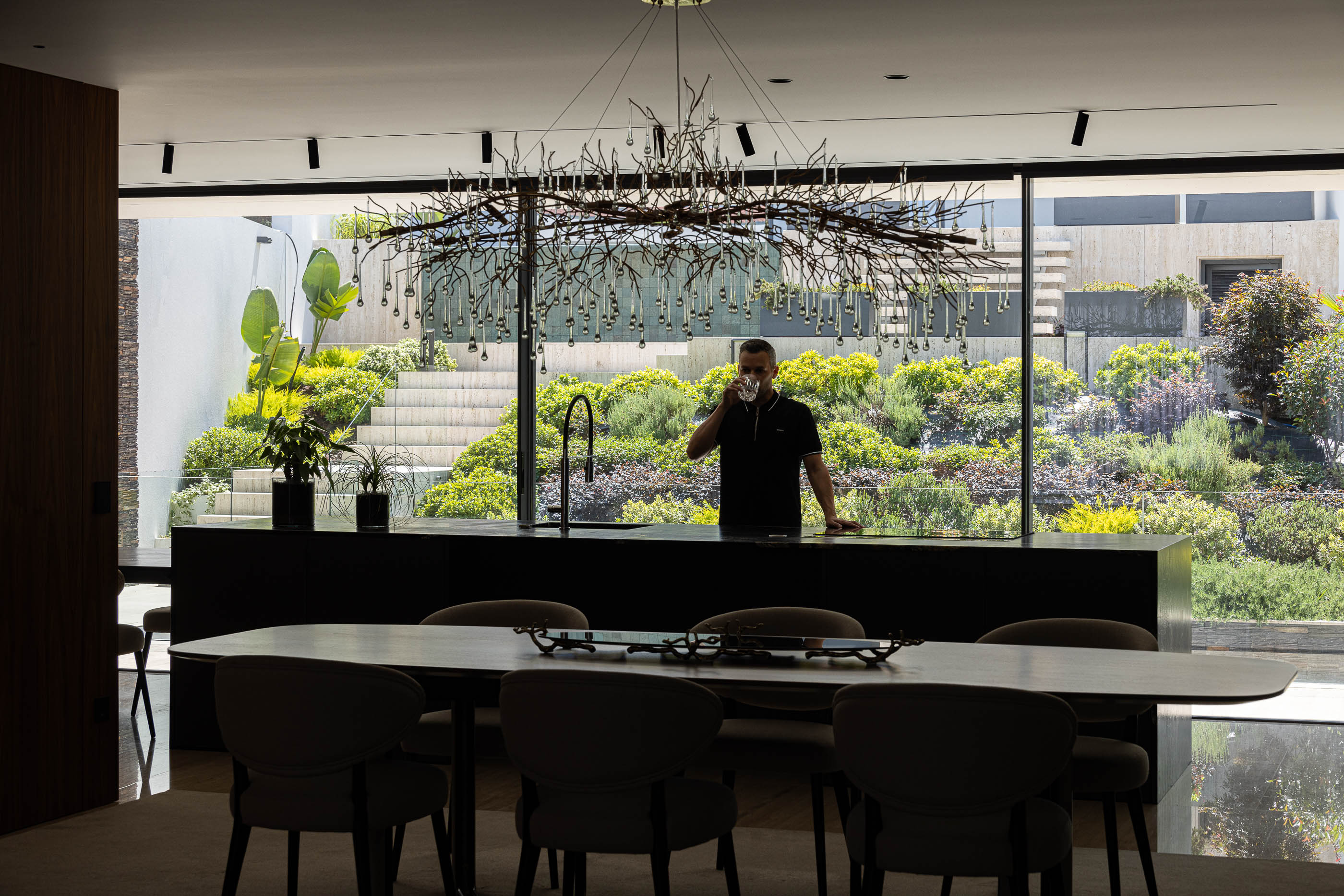 Sala de estar/jantar: Vista da ilha de cozinha com jardim vertical ao fundo. — Casa SA arquitetura Sandro Ferreira Arquitectura em Braga