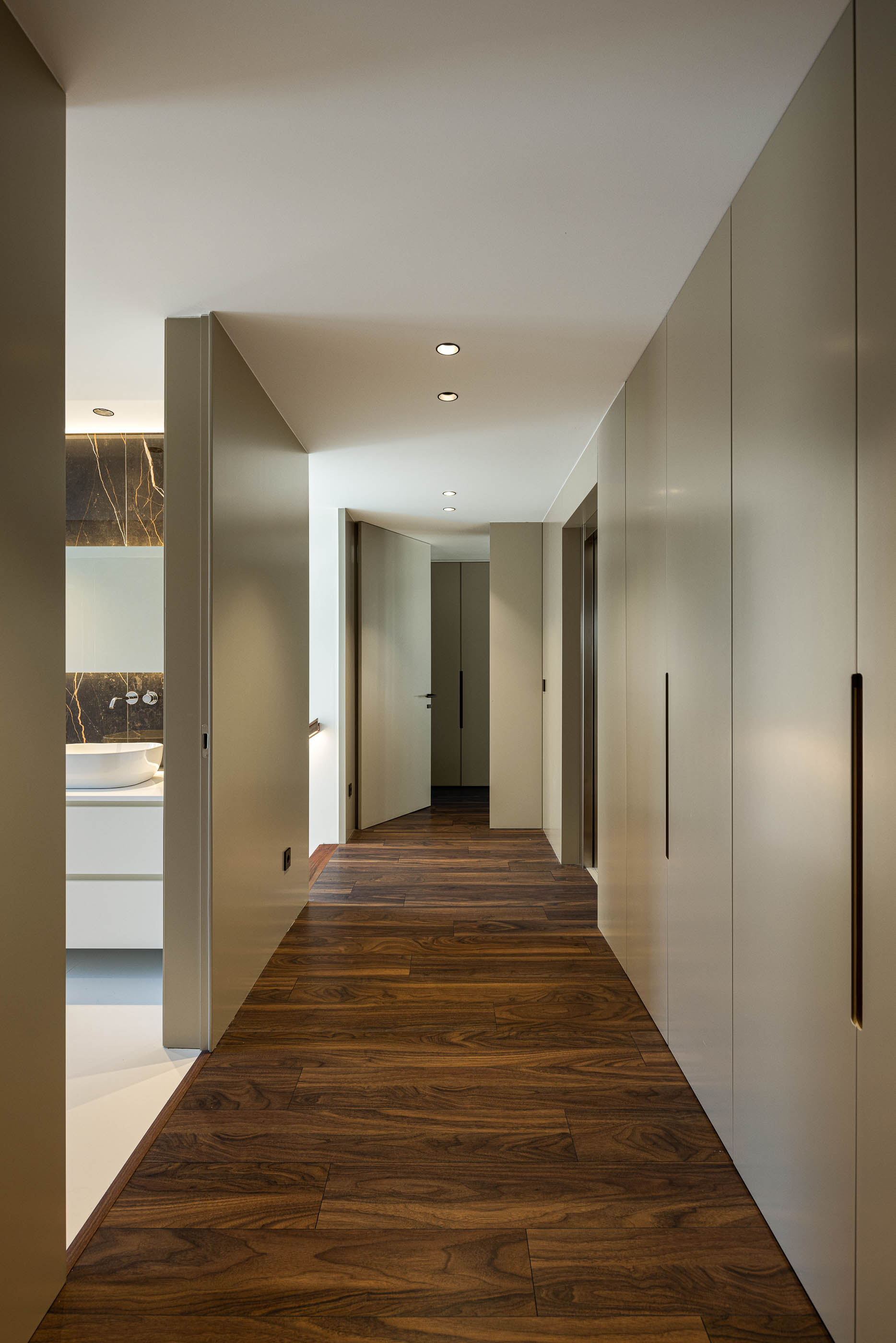 Corredor: Corredor com armários embutidos, pavimento em madeira e acesso à casa de banho. — Casa SA arquitetura Sandro Ferreira Arquitectura em Braga