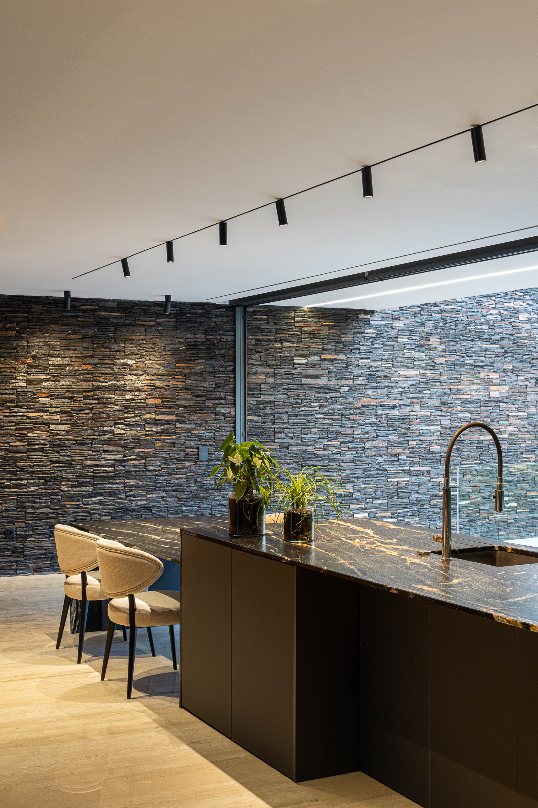 Cozinha: Ilha central com tampo em pedra escura e parede em pedra rústica. — Casa SA arquitetura Sandro Ferreira Arquitectura em Braga