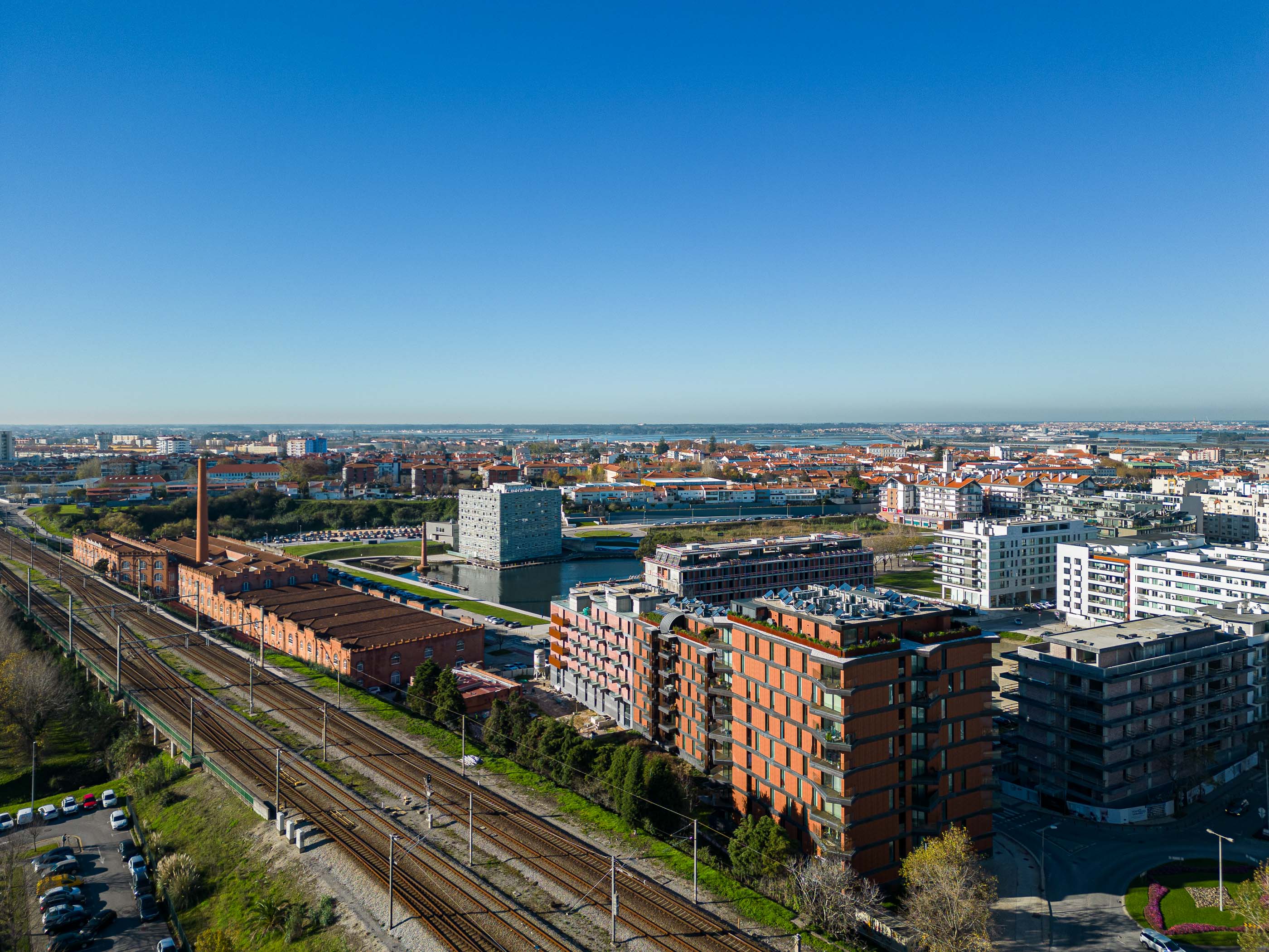 Paisagem urbana: Vista aérea de Aveiro com a torre residencial "Puro Tower" em destaque, junto à linha férrea e edifícios industriais. — Puro Tower arquitetura Mário Alves Arquitecto em Aveiro