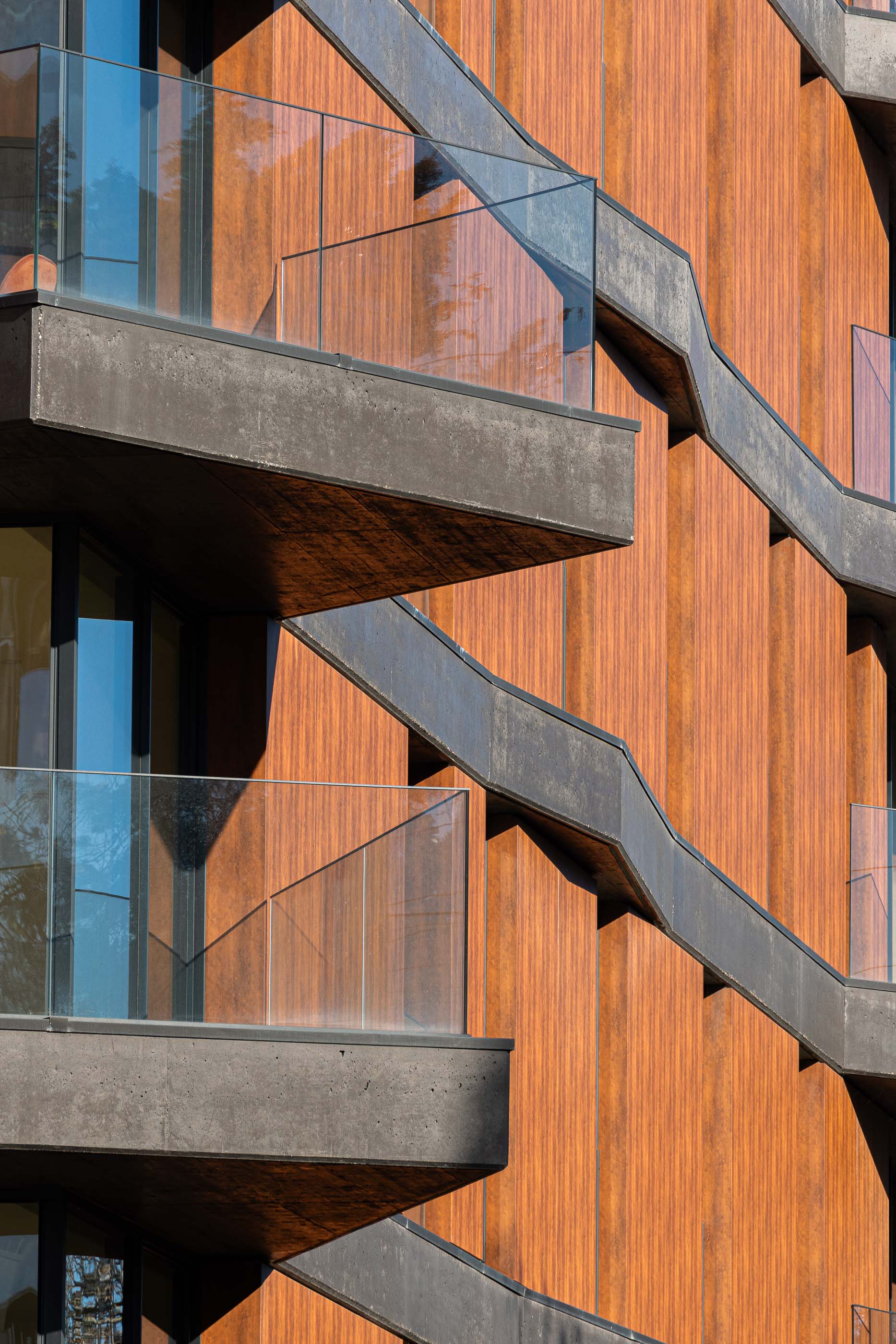 Fachada: Detalhe das varandas em betão com guardas de vidro e revestimento exterior em madeira. — Puro Tower arquitetura Mário Alves Arquitecto em Aveiro
