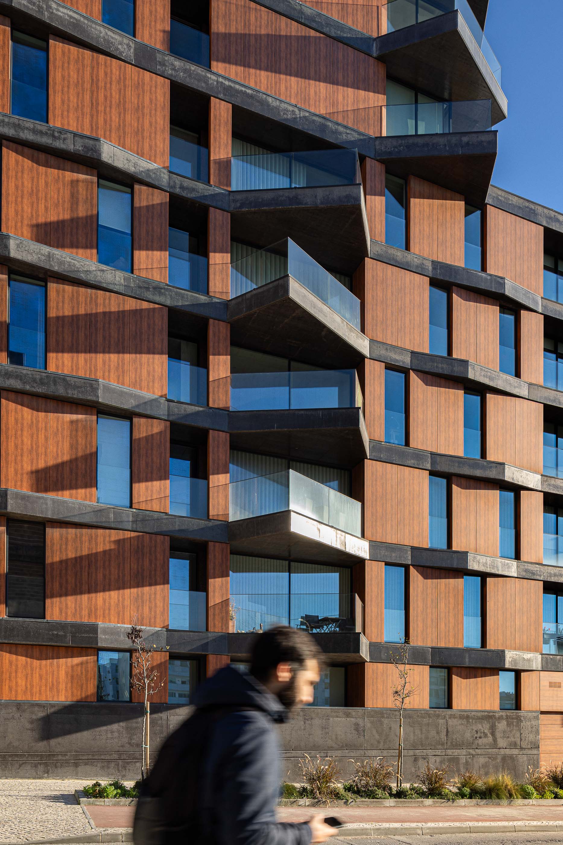 Fachada: Detalhe da fachada com varandas em betão e vidro, revestimento em madeira e janelas envidraçadas. — Puro Tower arquitetura Mário Alves Arquitecto em Aveiro