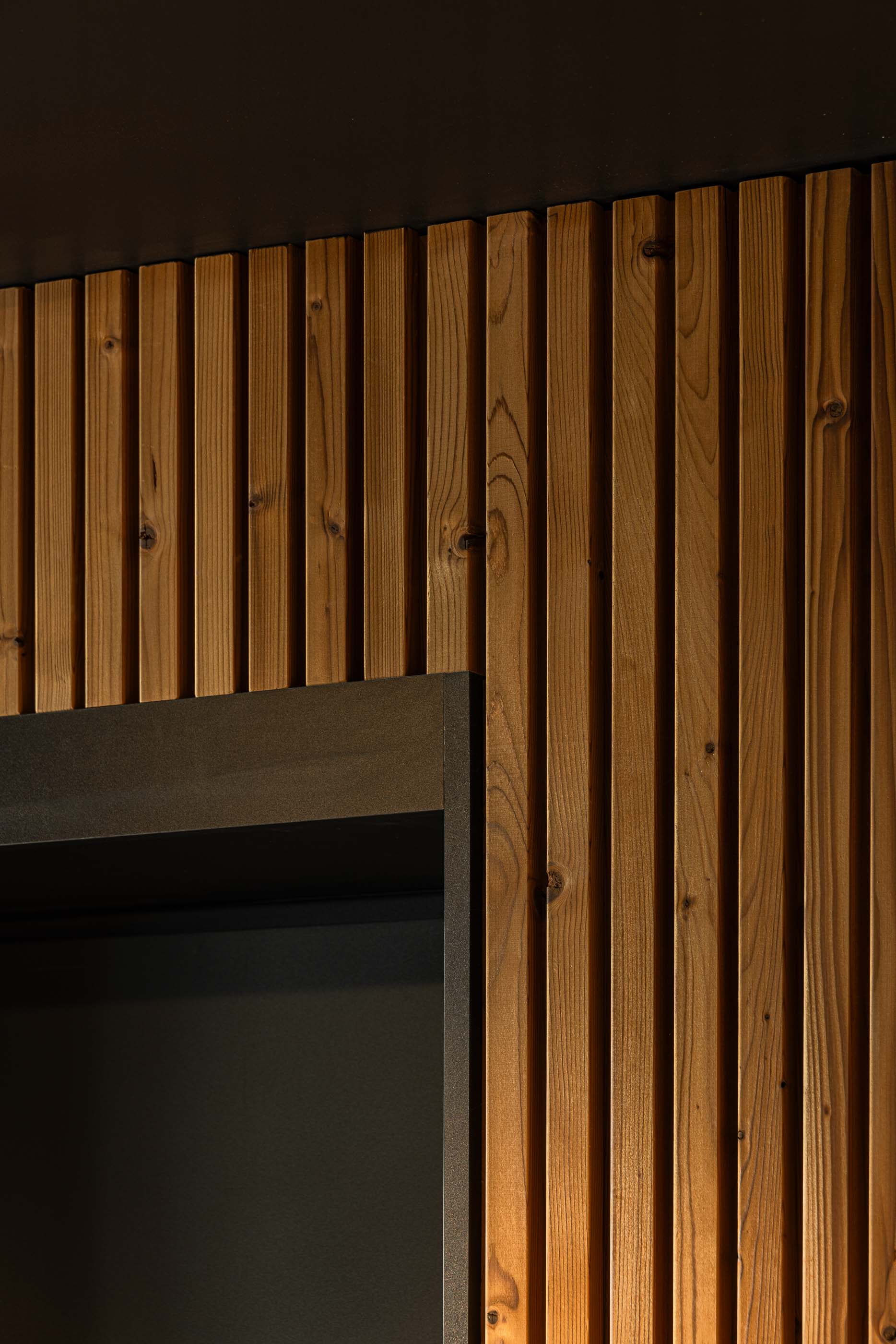 Corredor: Detalhe do revestimento em madeira vertical e da moldura preta de uma porta. — Puro Tower arquitetura Mário Alves Arquitecto em Aveiro