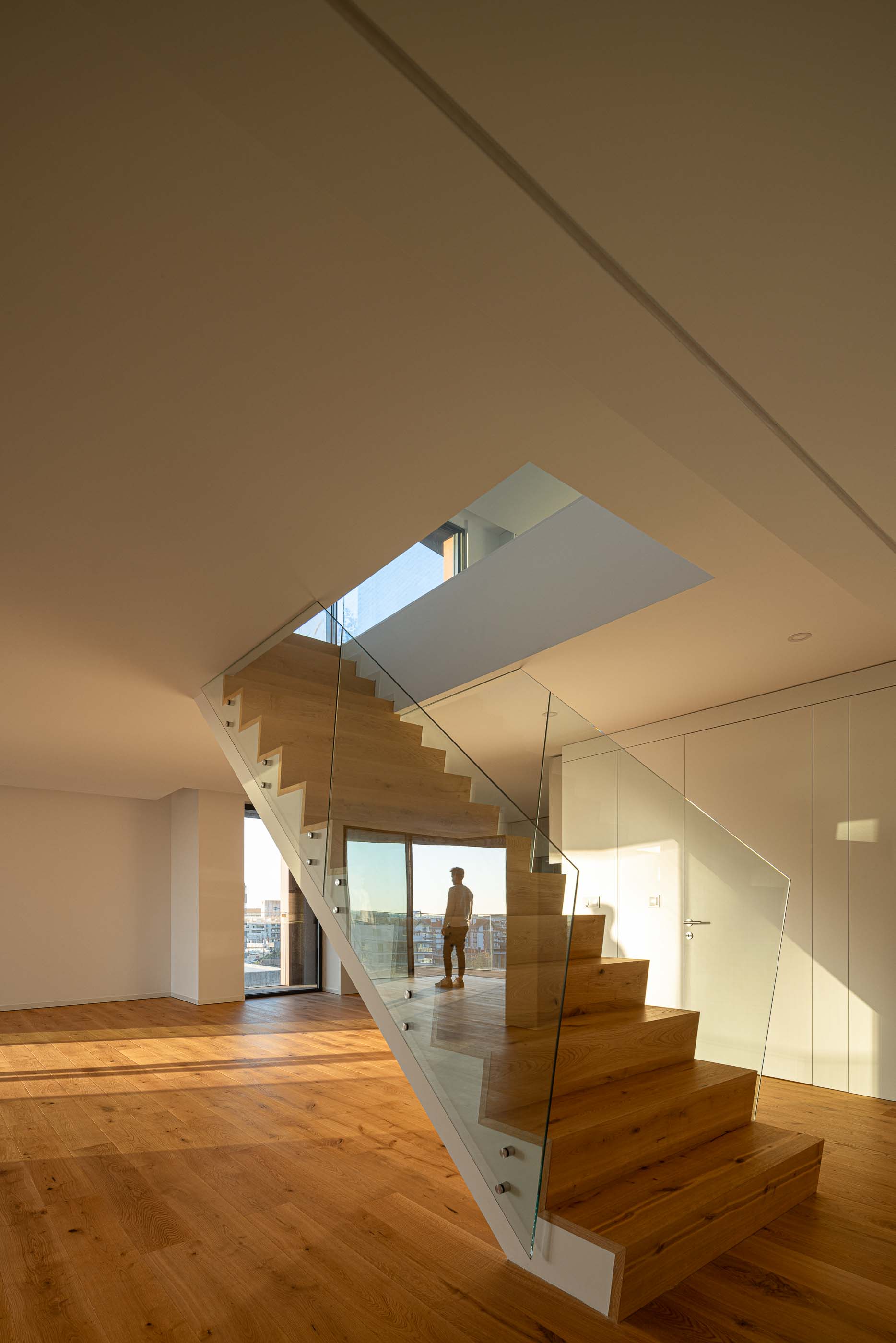 Escada: Escada em madeira com guardas de vidro, ligando dois pisos de um apartamento. — Puro Tower arquitetura Mário Alves Arquitecto em Aveiro