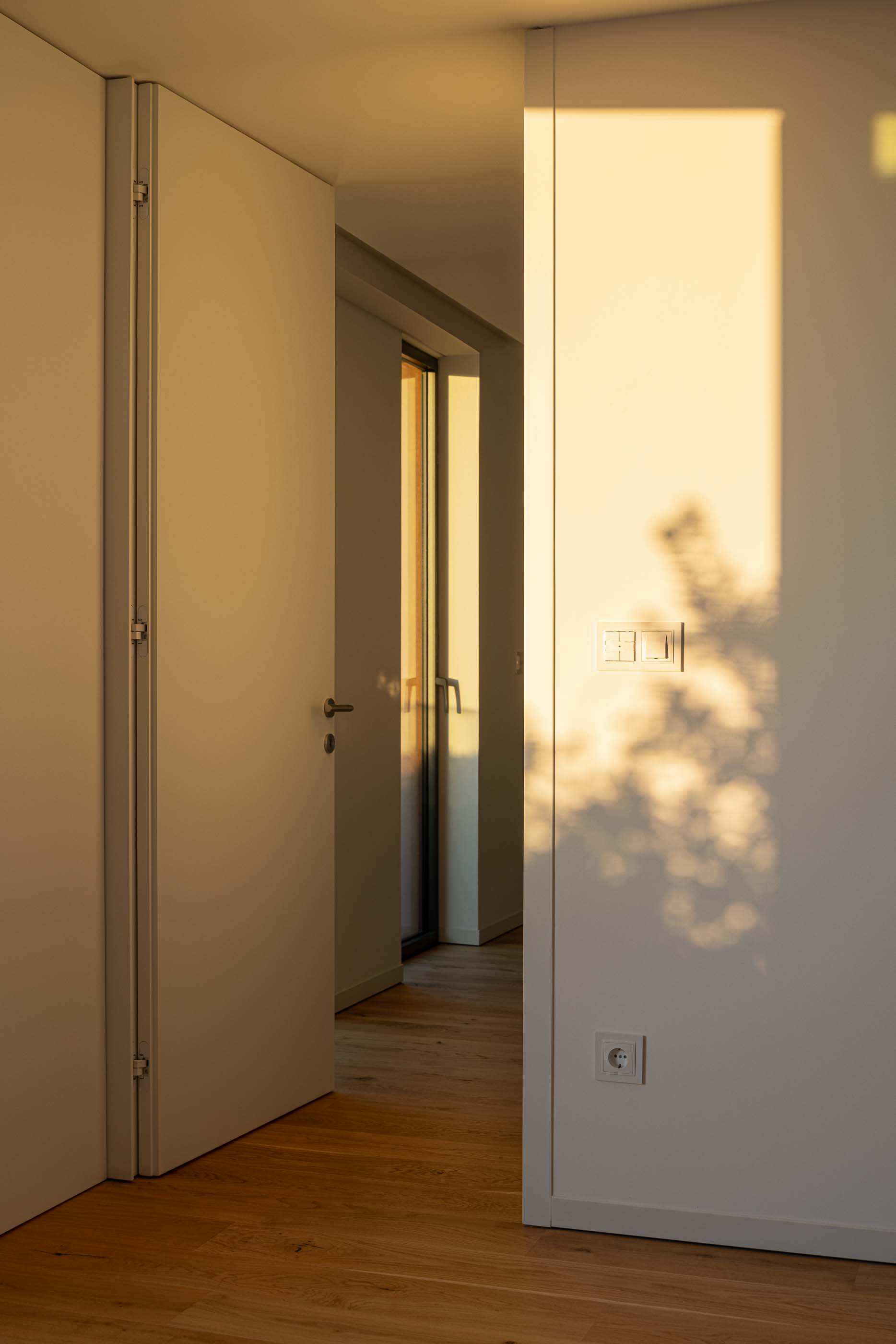 Quarto: Quarto com pavimento em madeira, paredes brancas e porta aberta para a varanda. — Puro Tower arquitetura Mário Alves Arquitecto em Aveiro