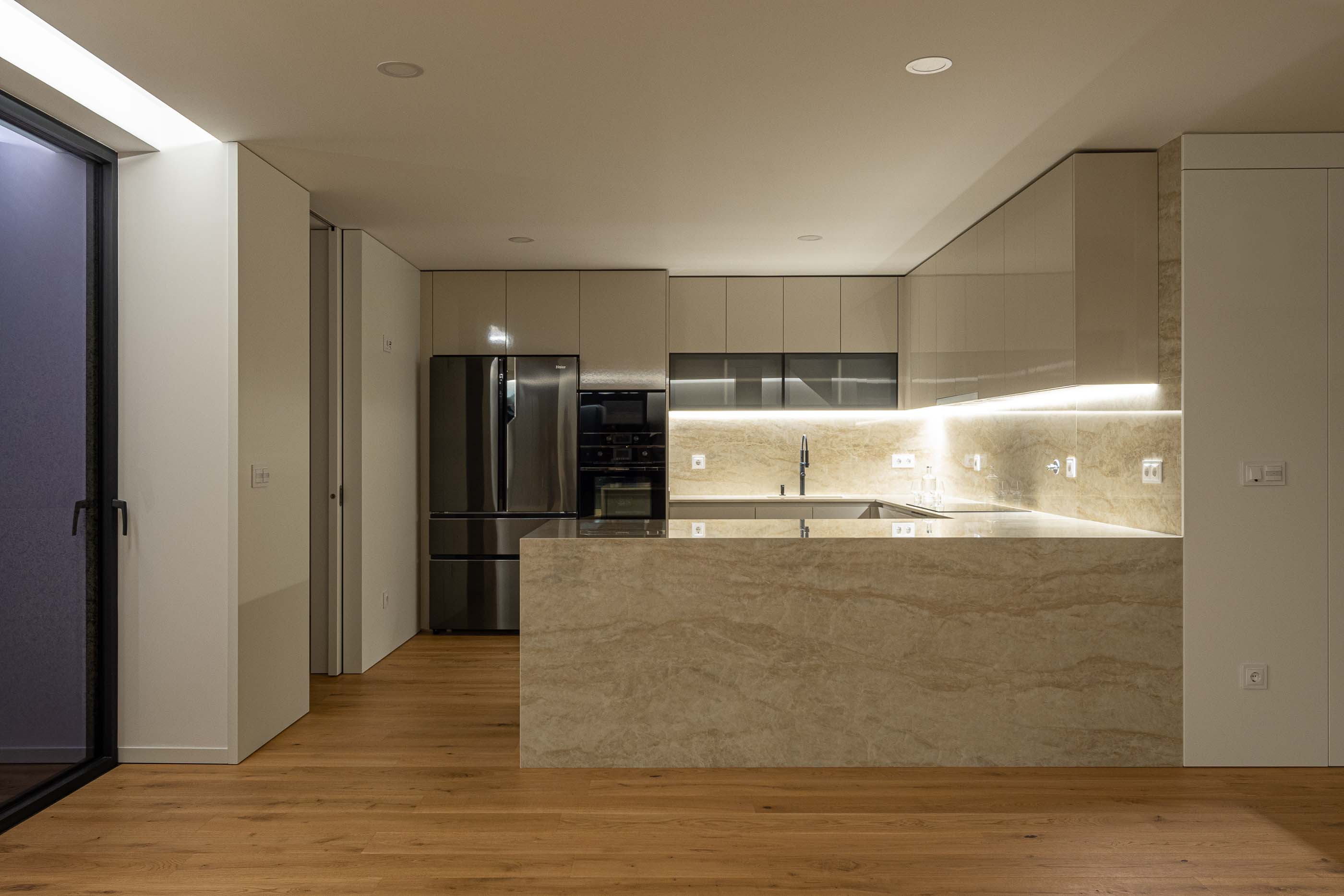 Cozinha: Cozinha moderna com armários brancos, bancada em mármore e pavimento em madeira. — Puro Tower arquitetura Mário Alves Arquitecto em Aveiro