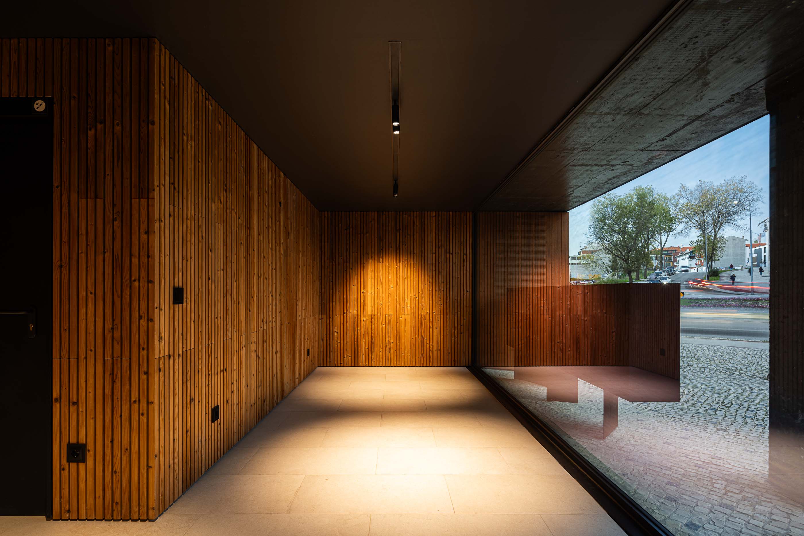 Hall de entrada: Hall de entrada com paredes revestidas a madeira, pavimento cerâmico e grandes janelas. — Puro Tower arquitetura Mário Alves Arquitecto em Aveiro