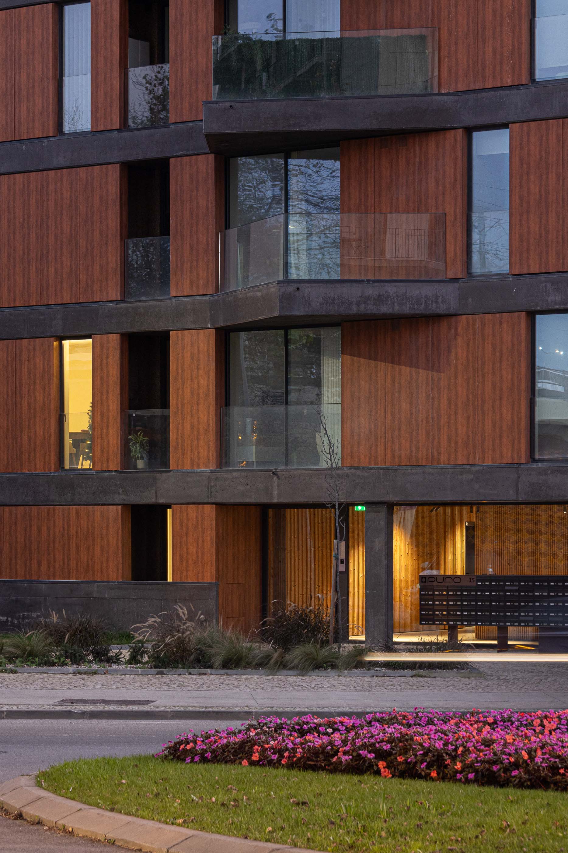 Entrada: Detalhe da entrada do edifício com revestimento em madeira, caixas de correio e vegetação. — Puro Tower arquitetura Mário Alves Arquitecto em Aveiro