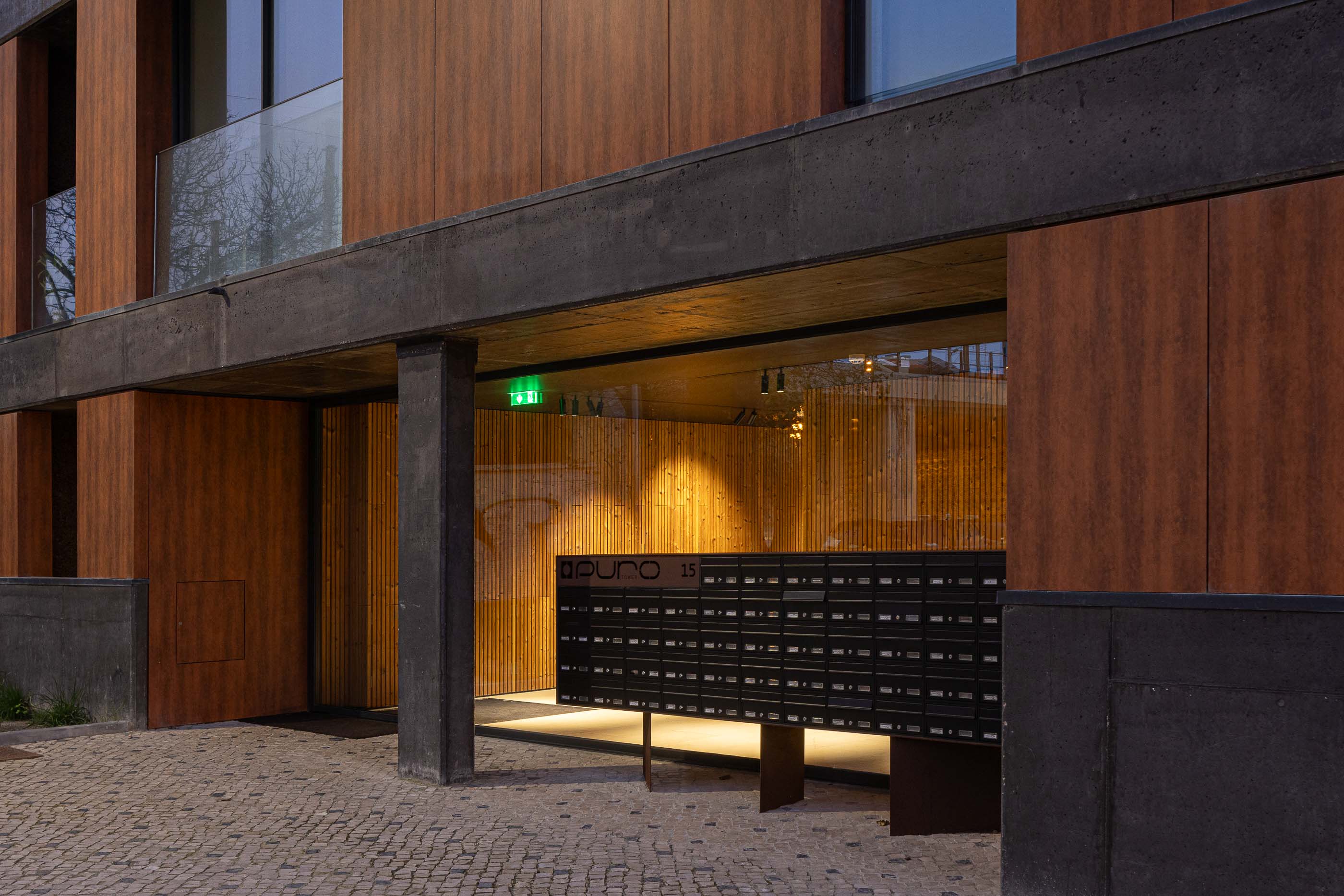 Entrada: Entrada do edifício com caixas de correio, revestimento em madeira e pavimento em calçada portuguesa. — Puro Tower arquitetura Mário Alves Arquitecto em Aveiro