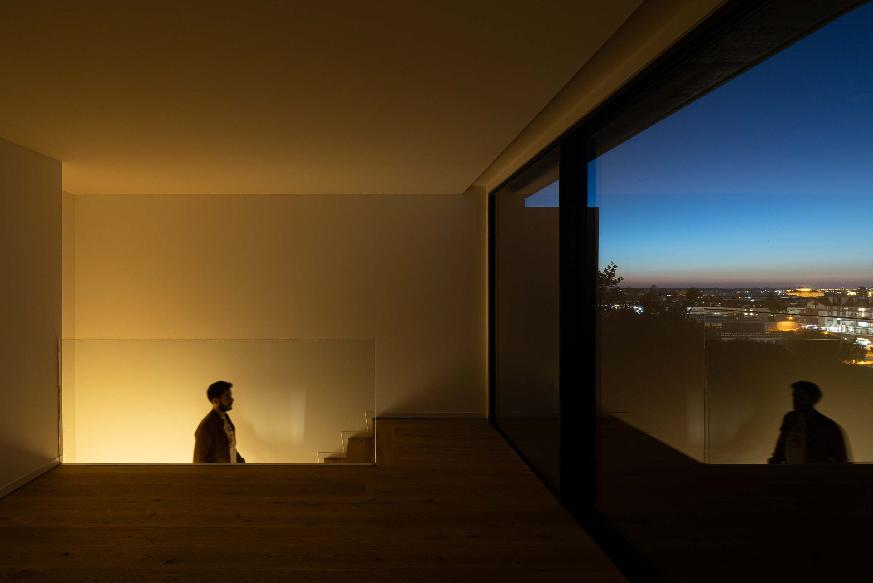 Sala de estar: Sala de estar com pavimento em madeira, grandes janelas e escada com guardas de vidro. — Puro Tower arquitetura Mário Alves Arquitecto em Aveiro