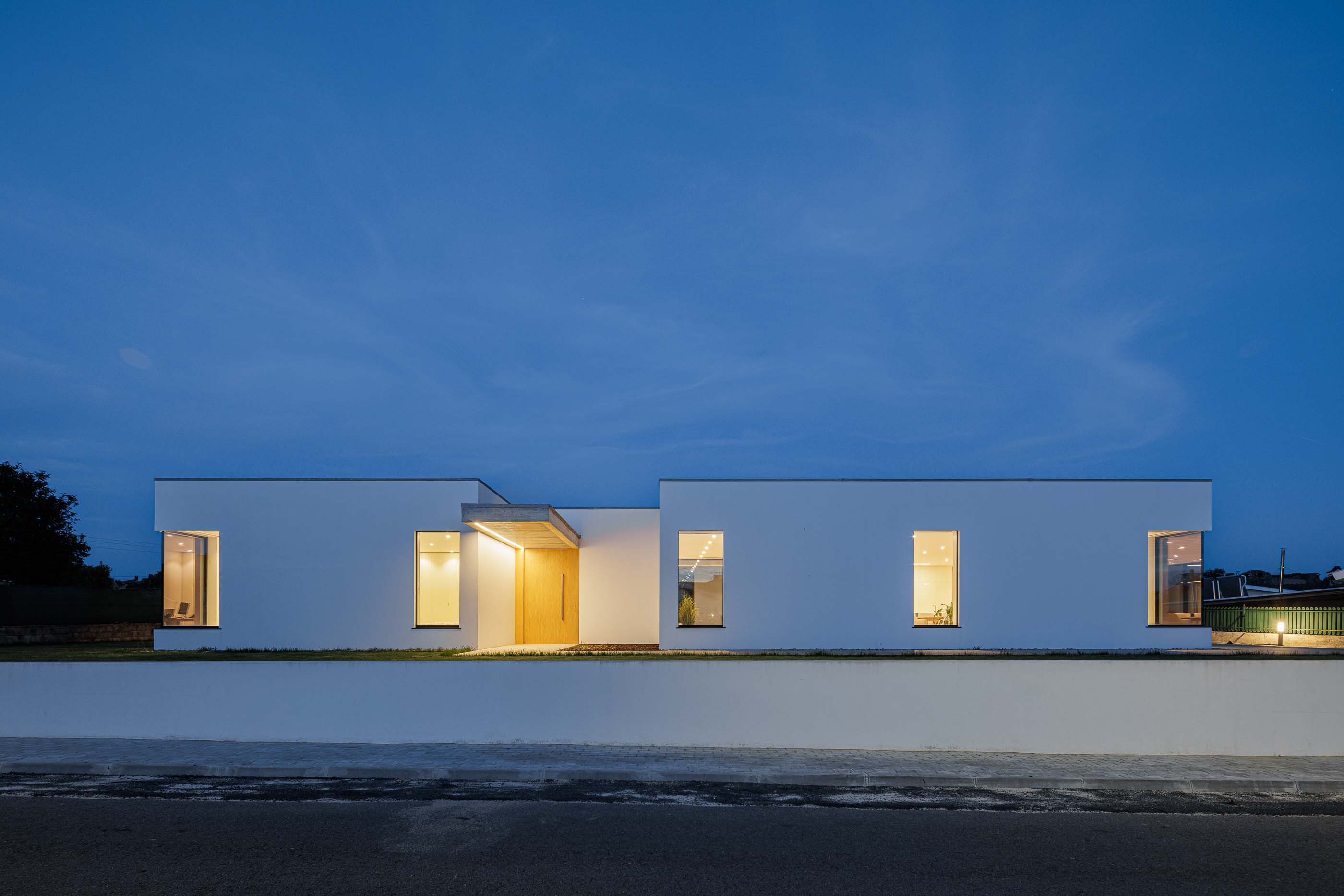 Exterior: Vista noturna da fachada da moradia com iluminação interior. — Casa CS arquitetura Jorge Gonzalez, WALAA em Águeda