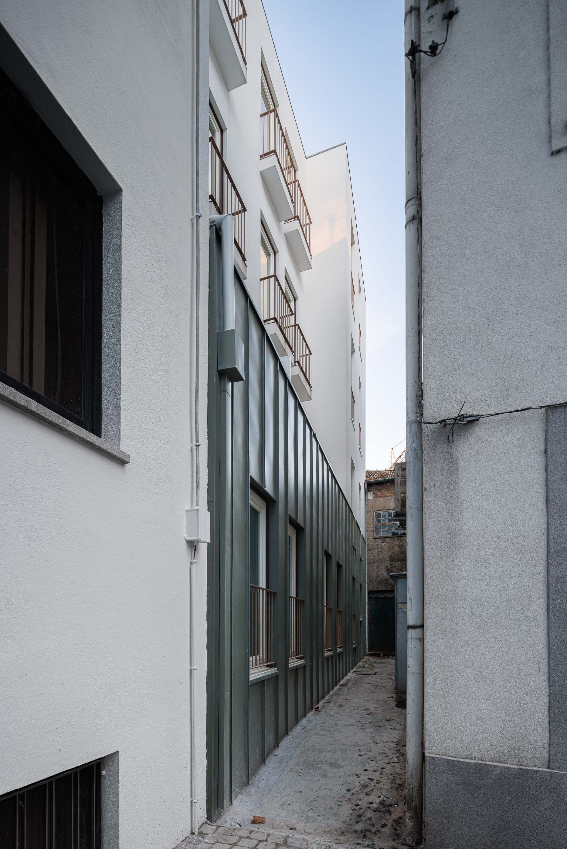 Exterior: Fachada lateral do edifício com revestimento metálico cinzento e varandas com gradeamento em ferro. — Apartamentos Vitória arquitetura Floret Arquitectura em Viseu