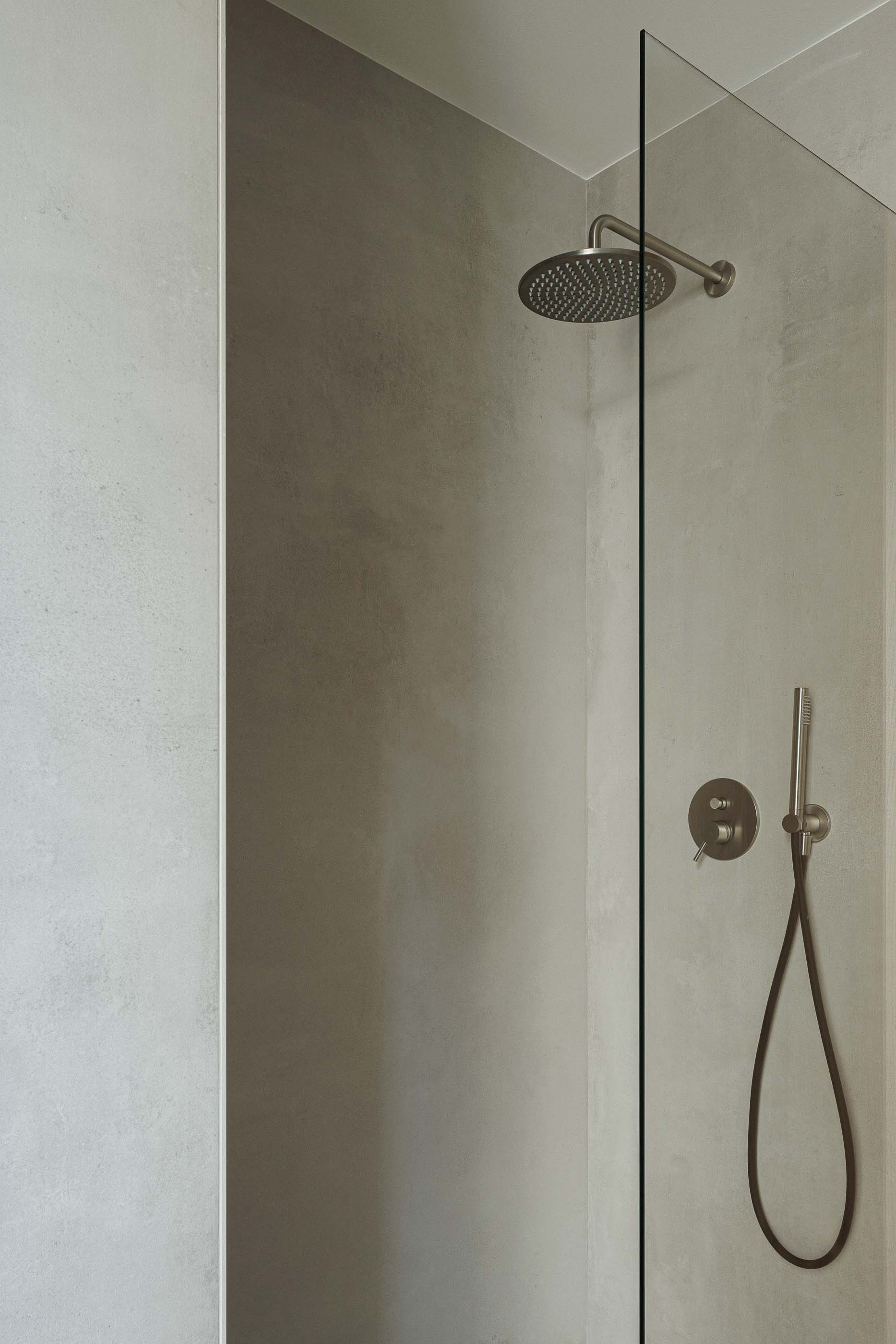 Casa de banho: Detalhe do chuveiro com resguardo em vidro e revestimento cinzento. — Apartamentos Vitória arquitetura Floret Arquitectura em Viseu