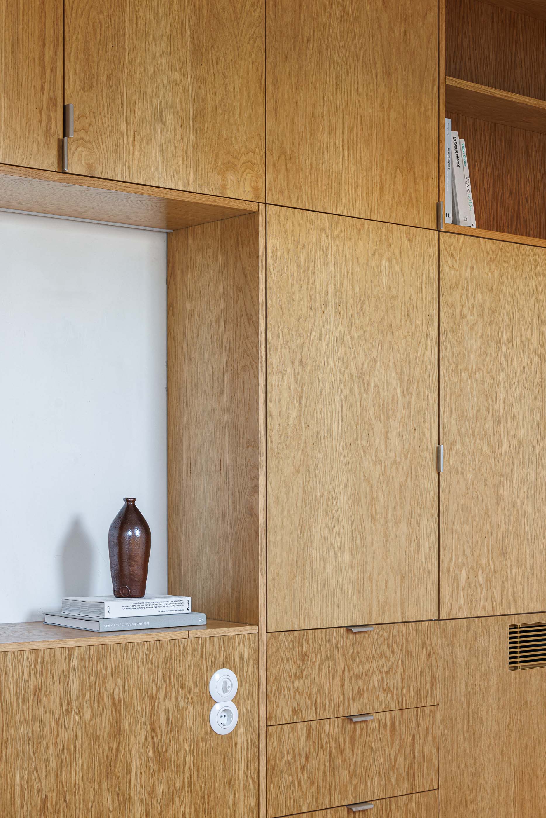 Quarto: Detalhe dos armários embutidos em madeira clara com prateleiras e tomadas. — Apartamentos Vitória arquitetura Floret Arquitectura em Viseu