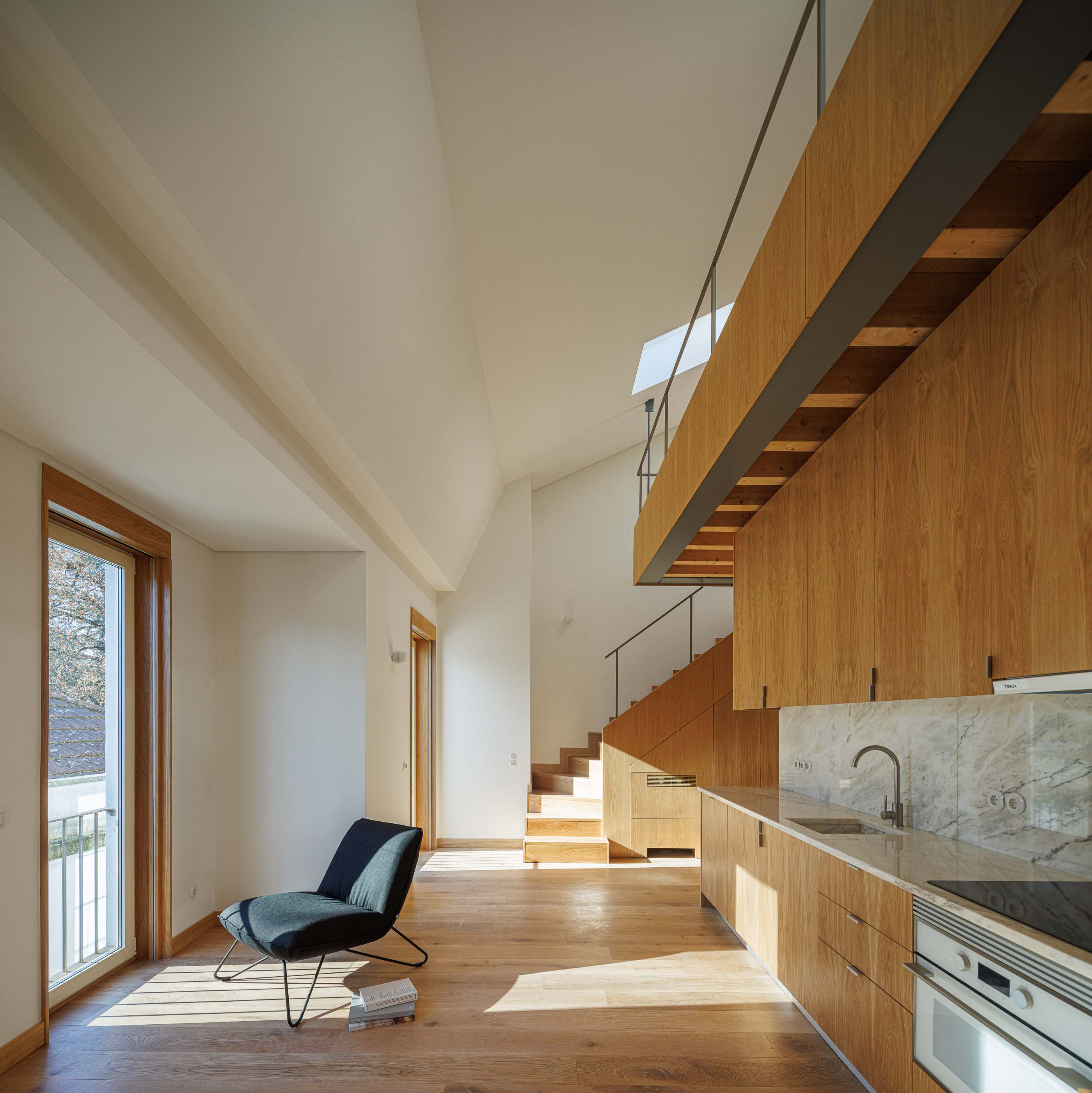 Sala de estar: Cozinha em madeira clara, mezzanine e janela com varanda num apartamento luminoso. — Apartamentos Vitória arquitetura Floret Arquitectura em Viseu