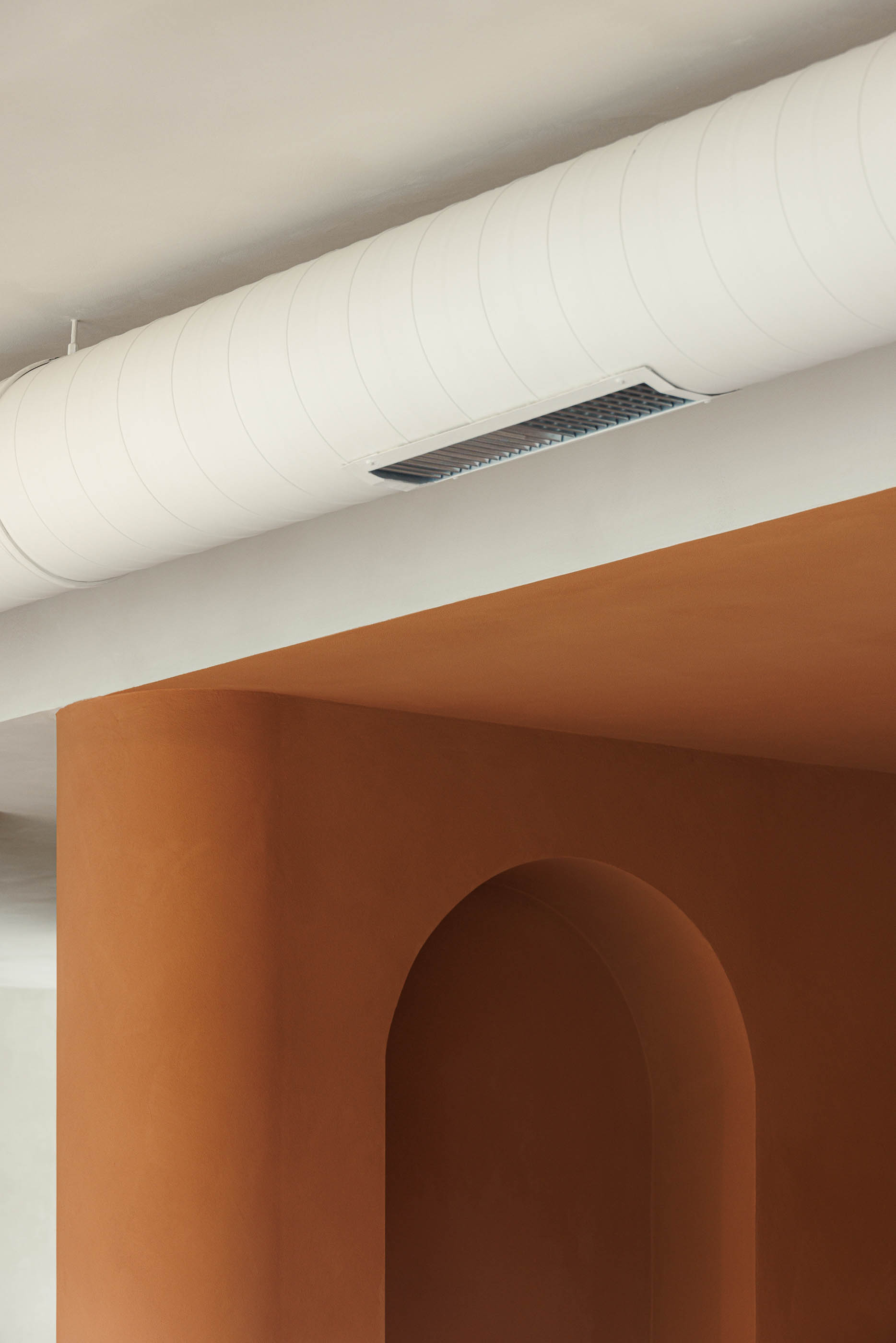Detalhe: Tubagem de ventilação, parede cor de tijolo com nicho em arco. — Level Private Gym arquitetura stu.dere em Penafiel
