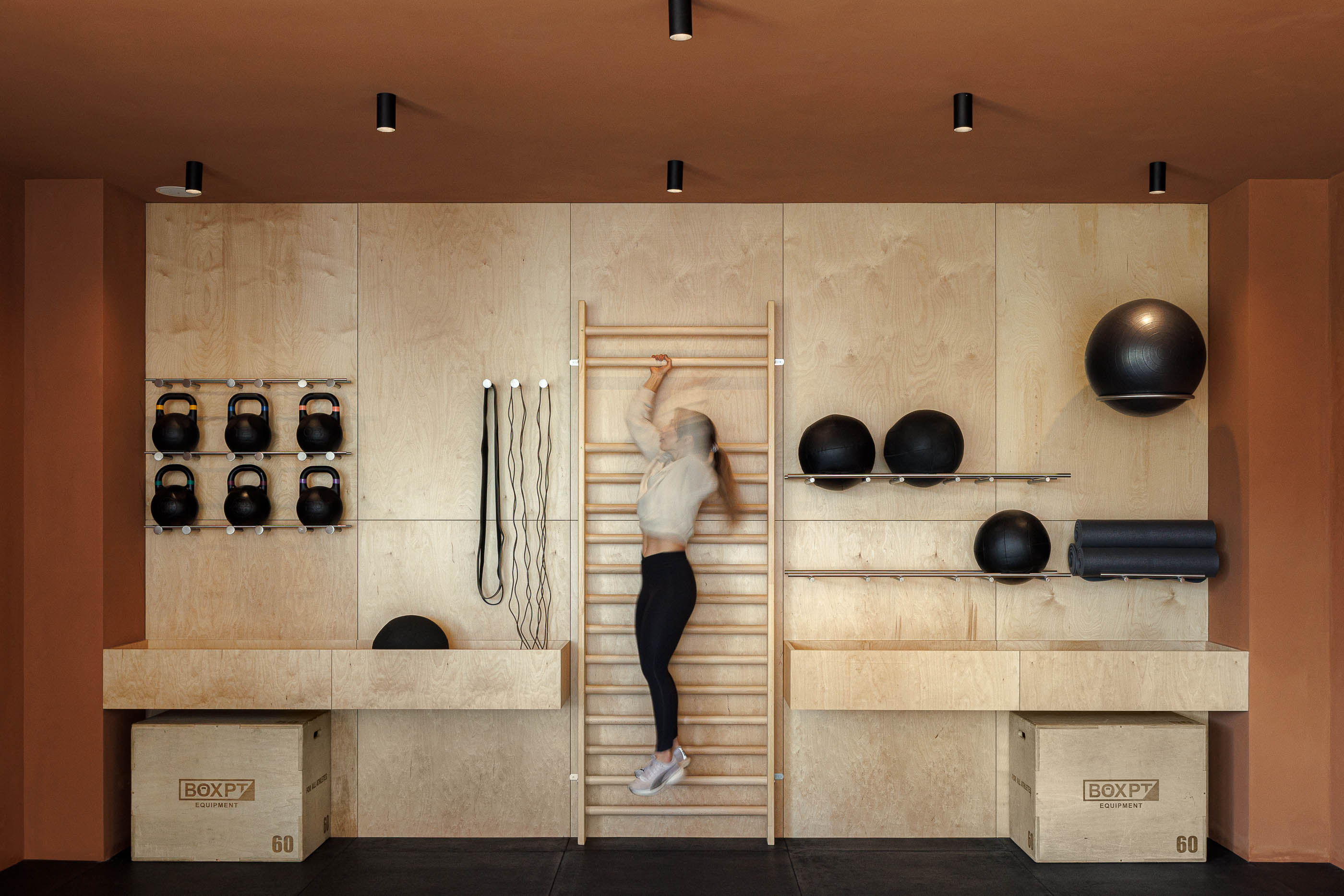 Sala de treino funcional: Mulher a treinar com escada de corda, parede em contraplacado e cor de tijolo. — Level Private Gym arquitetura stu.dere em Penafiel