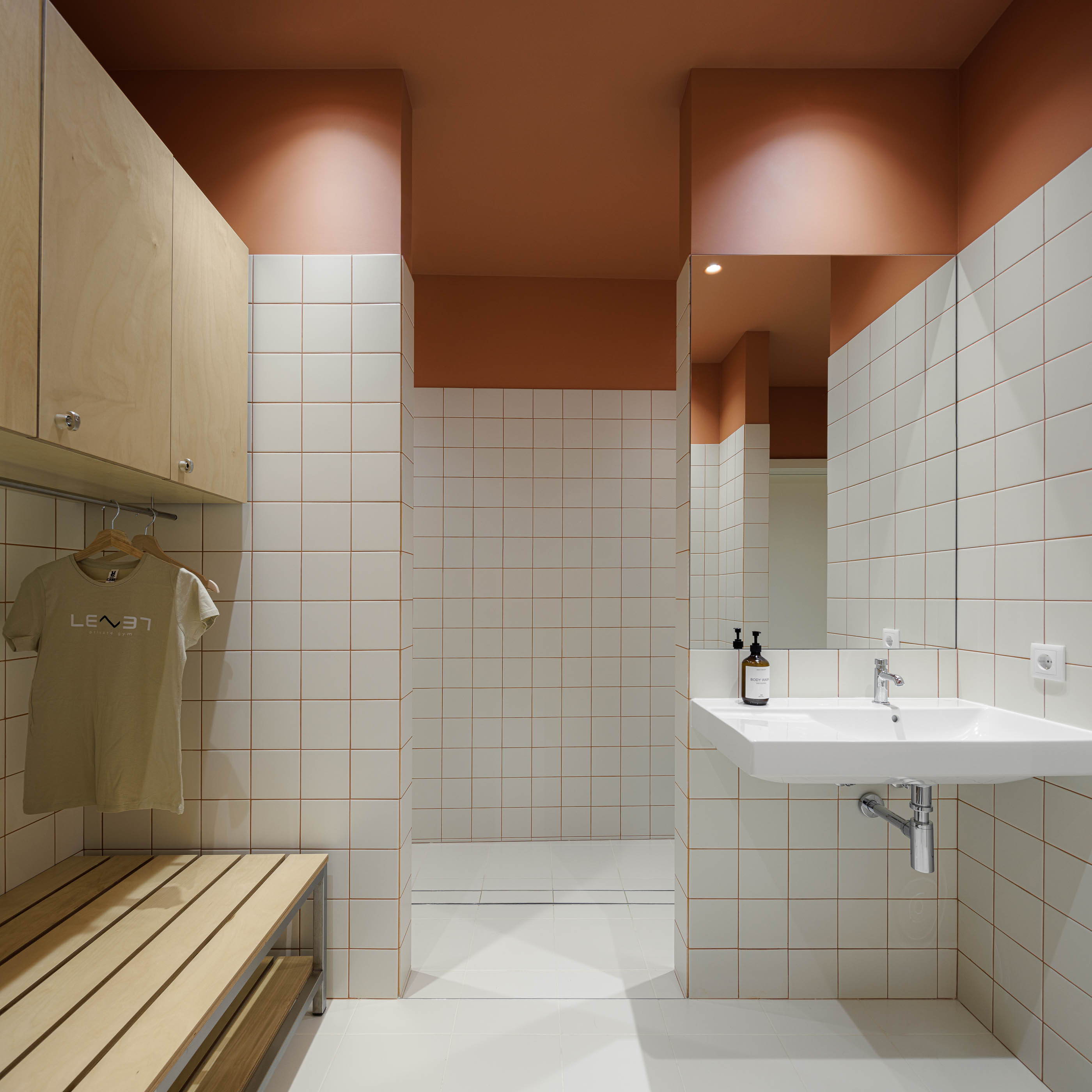 Vestiário: Porta branca, azulejos brancos com juntas cor de laranja, pavimento cerâmico claro. — Level Private Gym arquitetura stu.dere em Penafiel