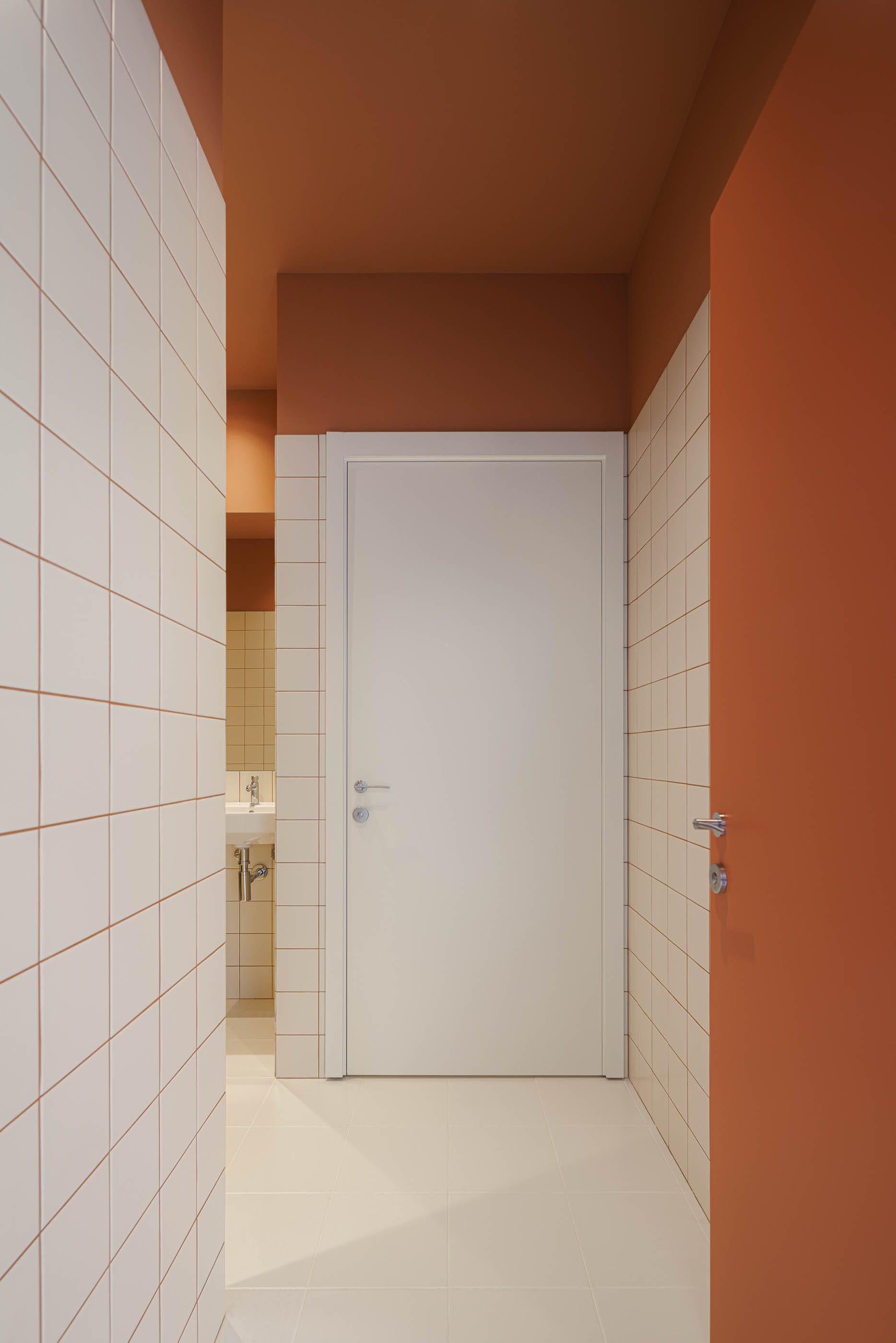 Entrada: Porta cor de tijolo, candeeiro esférico, vista para sala com cadeiras de madeira. — Level Private Gym arquitetura stu.dere em Penafiel