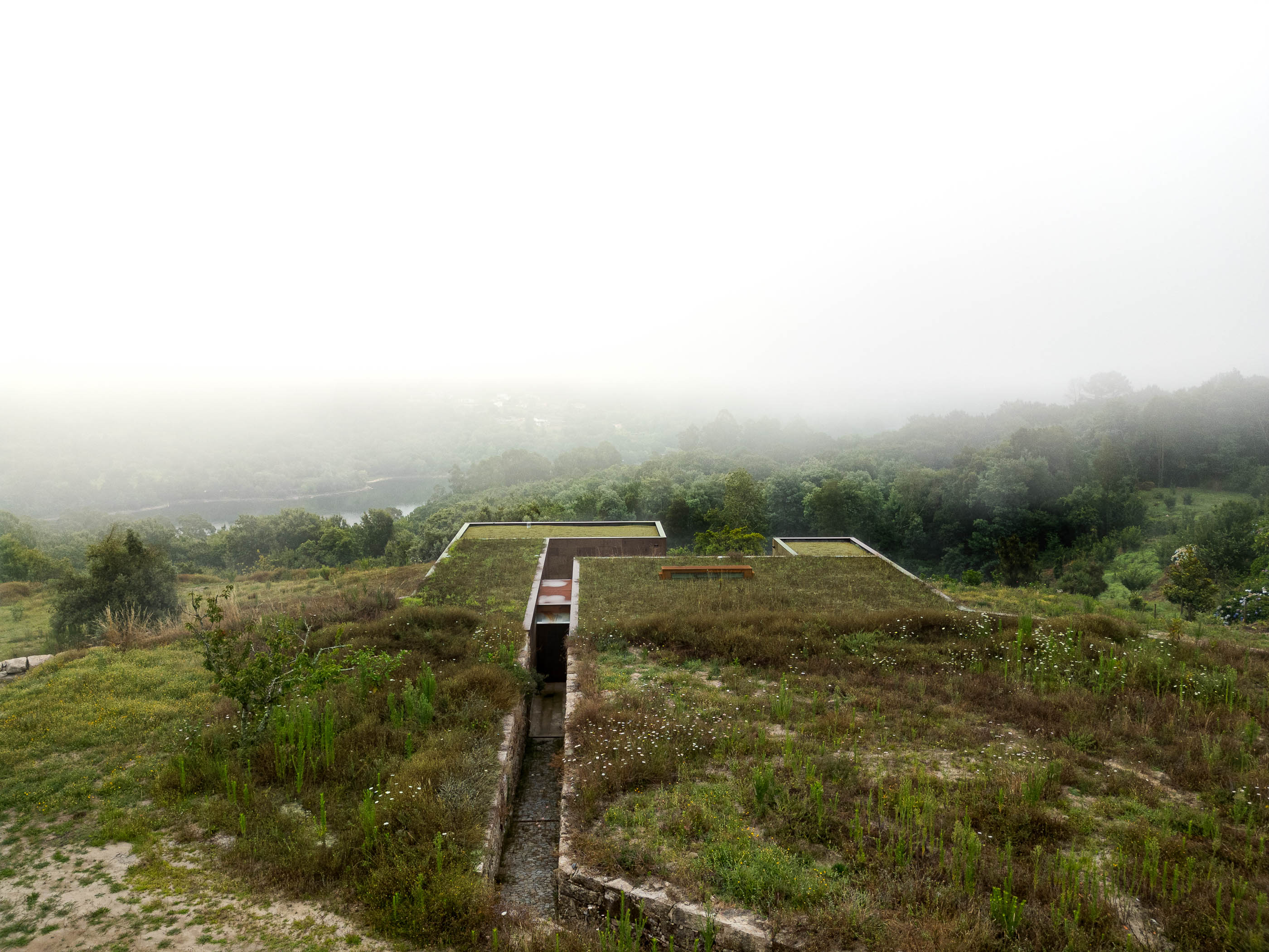 Exterior: Vista superior da casa com telhado verde, integrando-se na paisagem rural. — Casa da Levada arquitetura Tsou Arquitectos em Penafiel