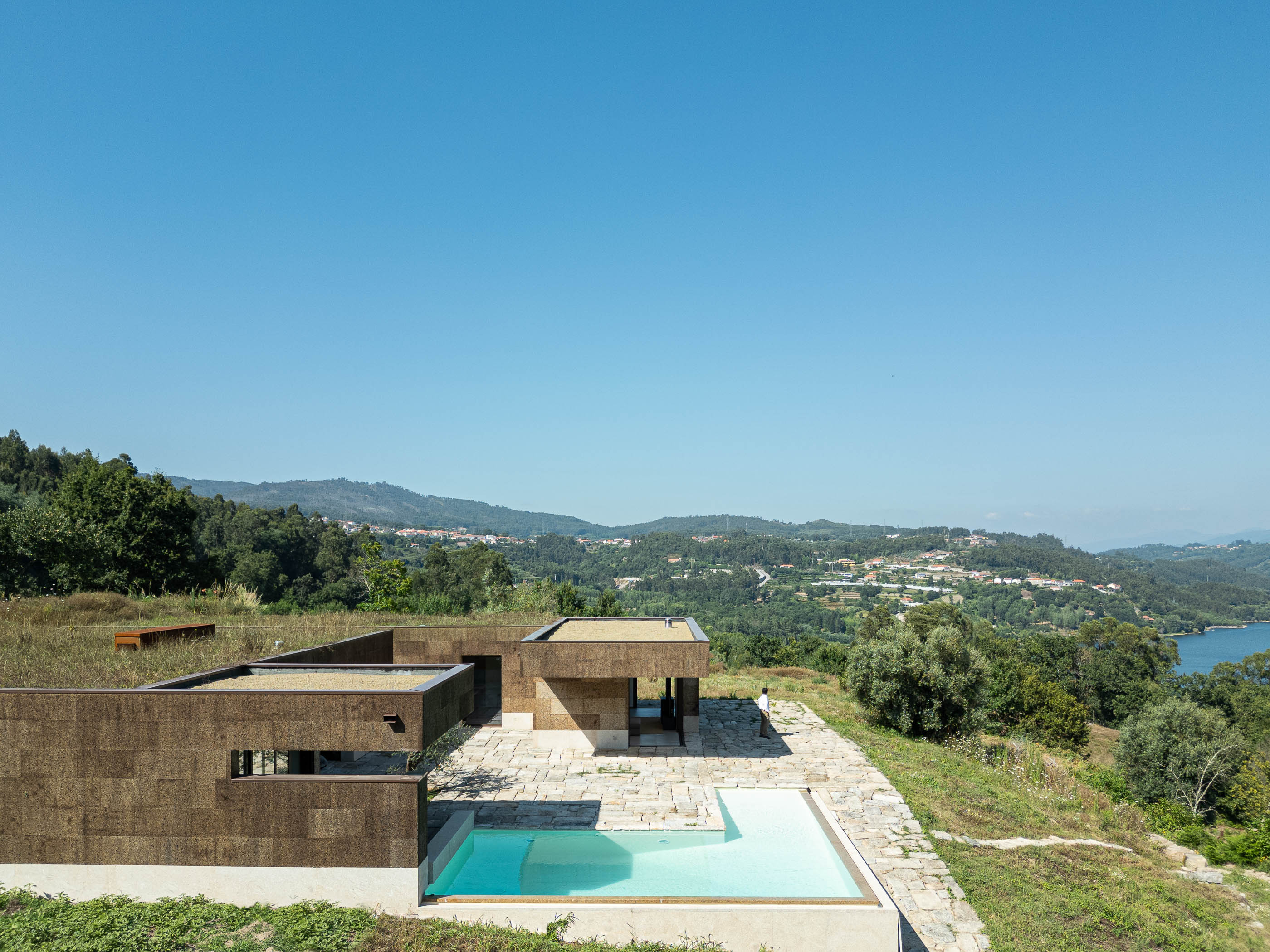 Exterior: Vista aérea da casa com piscina, pátio em pedra e paisagem natural. — Casa da Levada arquitetura Tsou Arquitectos em Penafiel