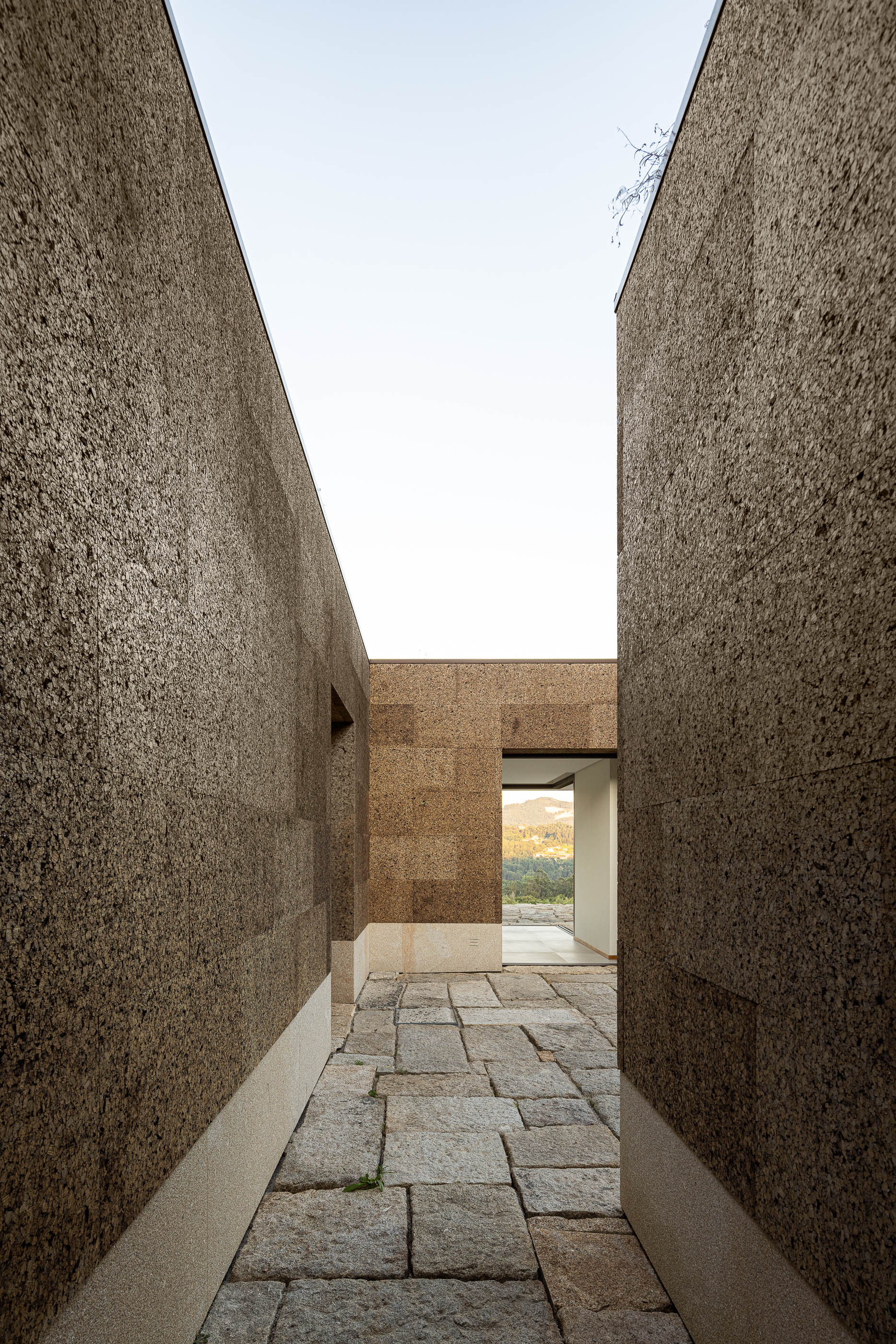 Exterior: Passadiço entre paredes em cortiça, com pavimento em pedra. — Casa da Levada arquitetura Tsou Arquitectos em Penafiel