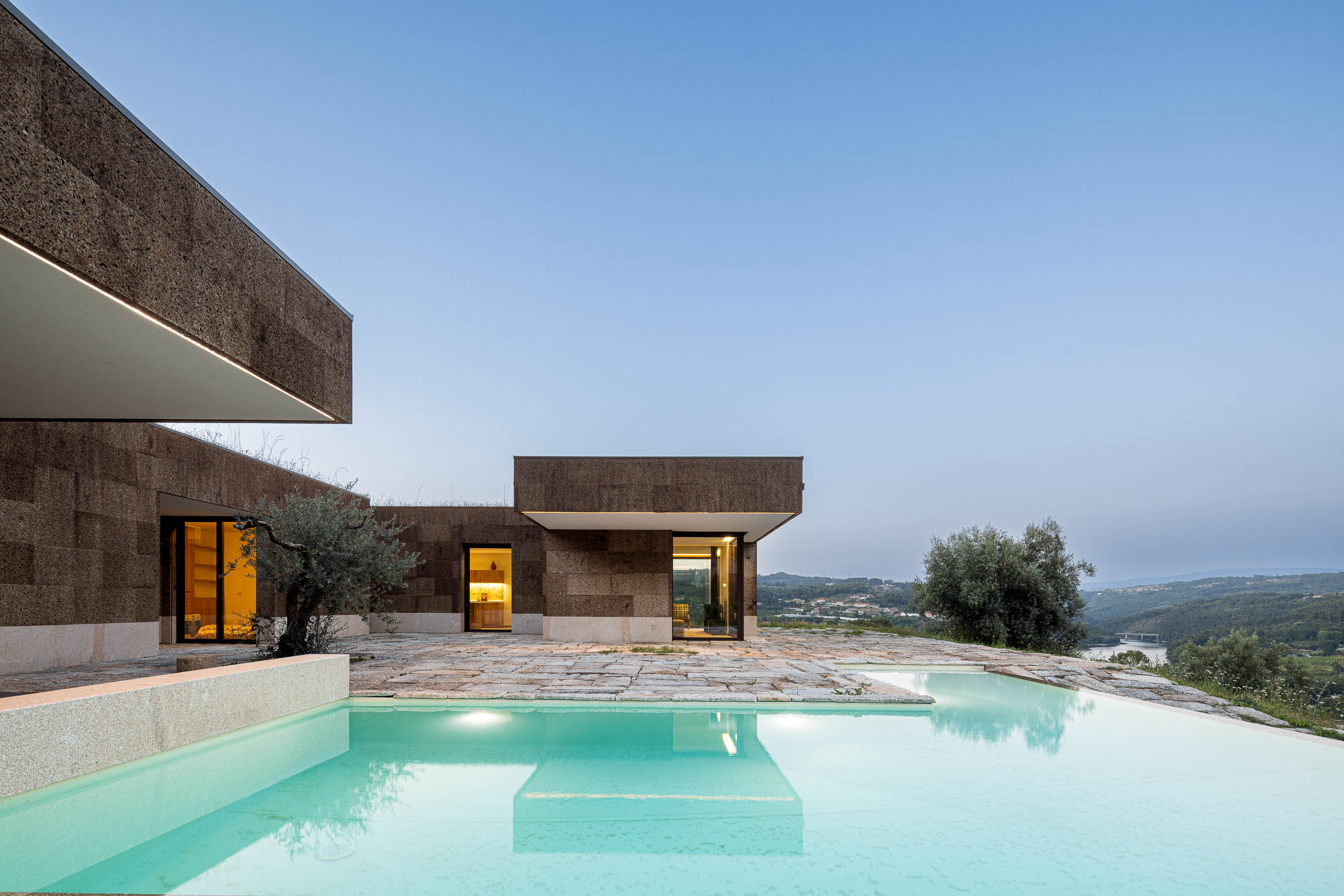 Exterior: Fachada da casa com piscina, pátio em pedra e iluminação exterior. — Casa da Levada arquitetura Tsou Arquitectos em Penafiel