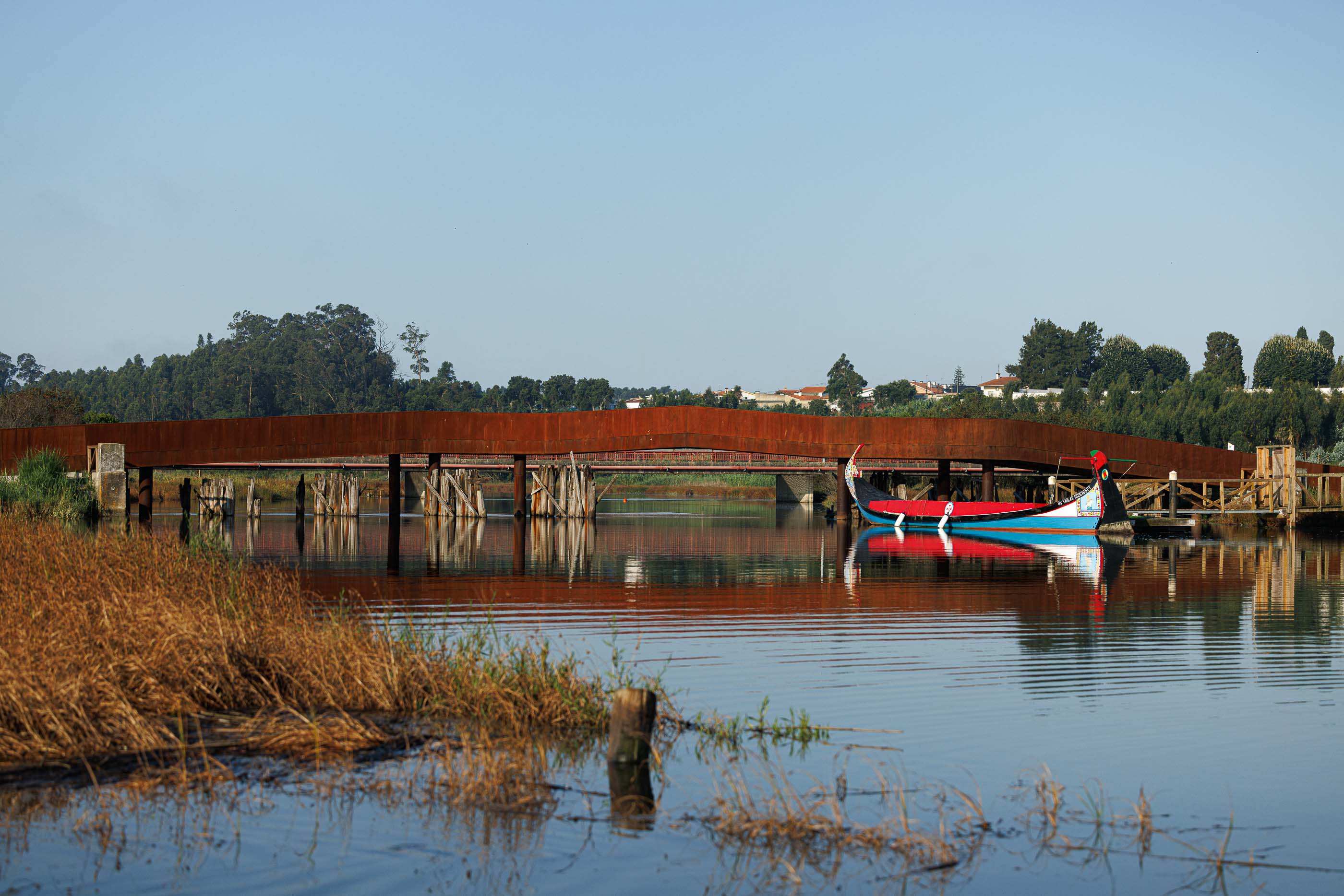 Ponte: Entrada da ponte com passadiço em terra batida e estrutura em aço corten. — Requalificação da antiga Ponte da Fareja arquitetura Rómulo Neto Arquitectos em Aveiro