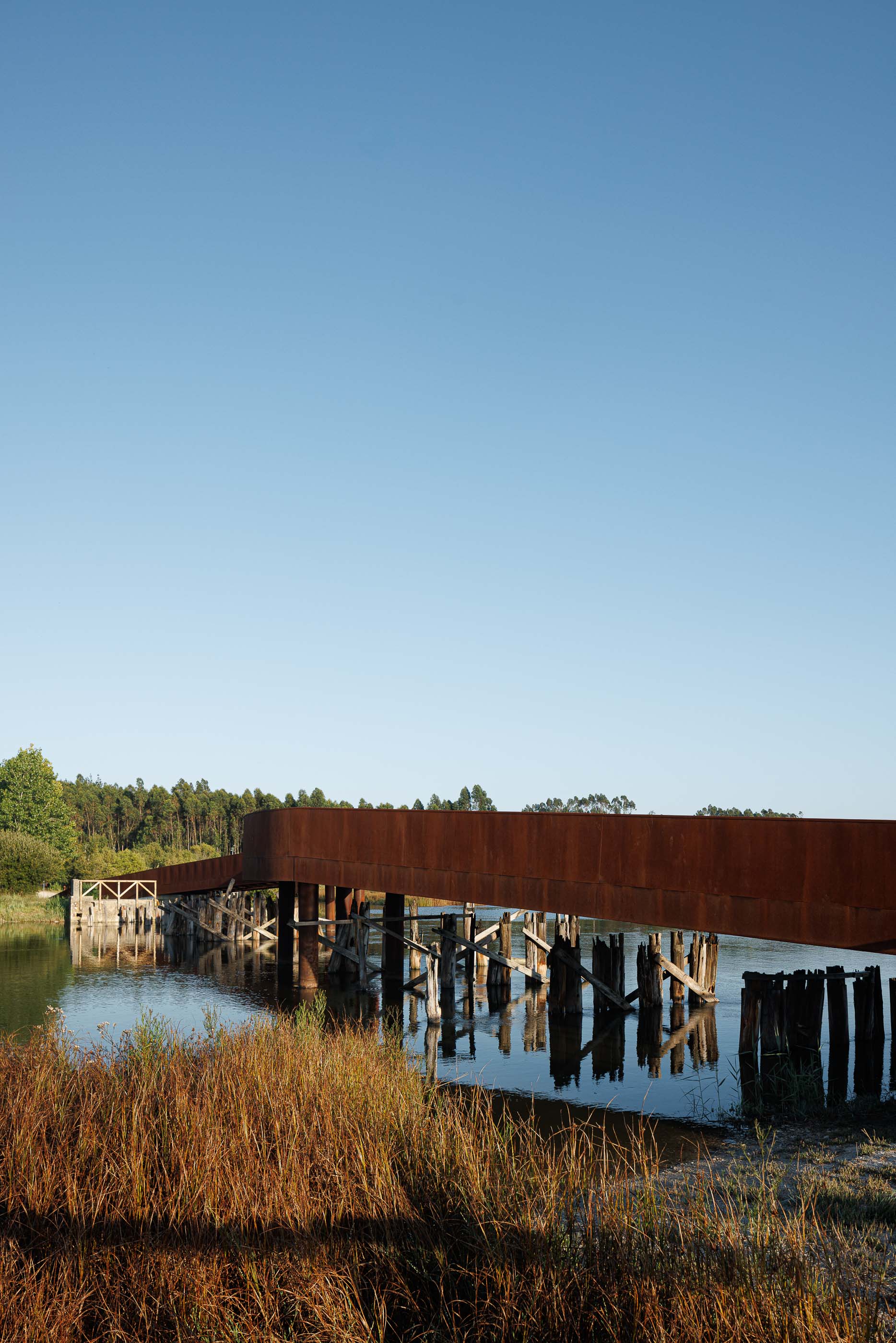 Ponte: Família sentada num banco de madeira na ponte, a apreciar a paisagem. — Requalificação da antiga Ponte da Fareja arquitetura Rómulo Neto Arquitectos em Aveiro